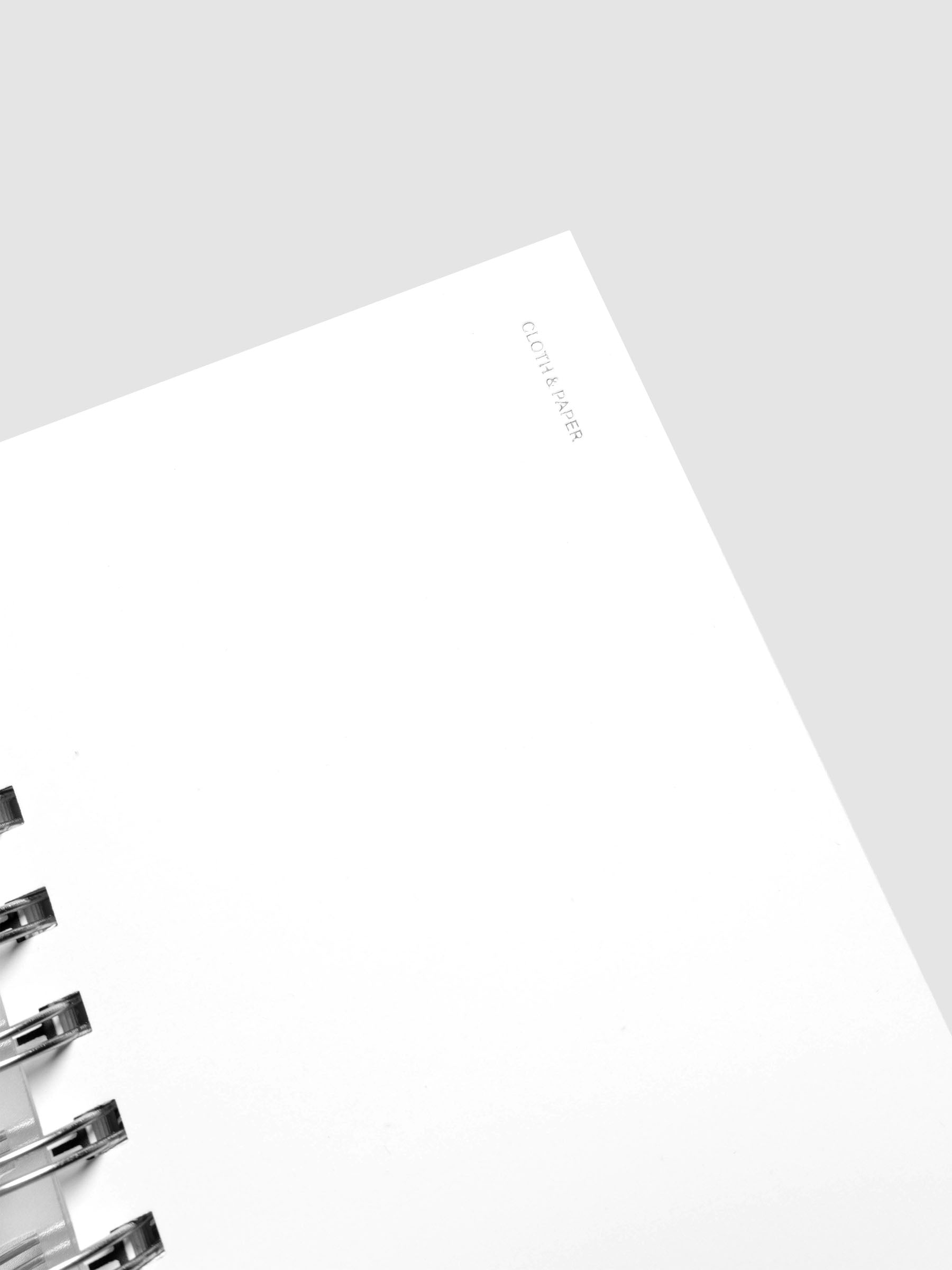 Detail view of the Spiral Notebook dashboard in the color Le Blanc shown in size CP Petite against a neutral background.