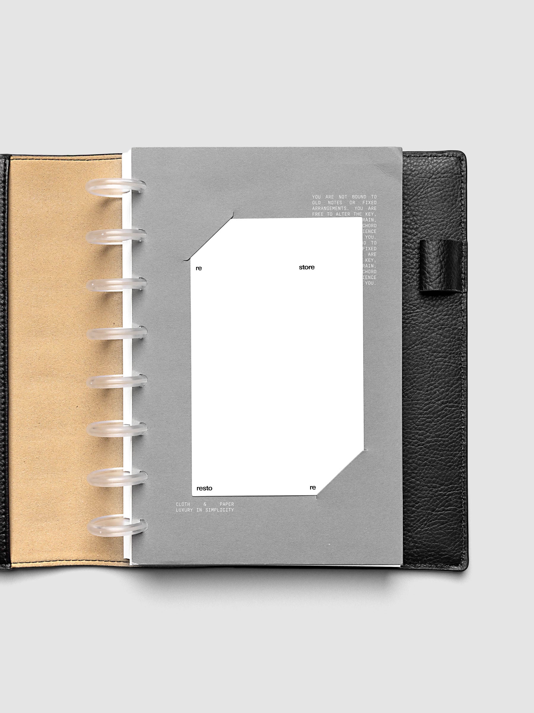Grey cardstock planner dashboard with white plastic card inserted in slits with white printed text shown in size Half Letter in a discbound planner.