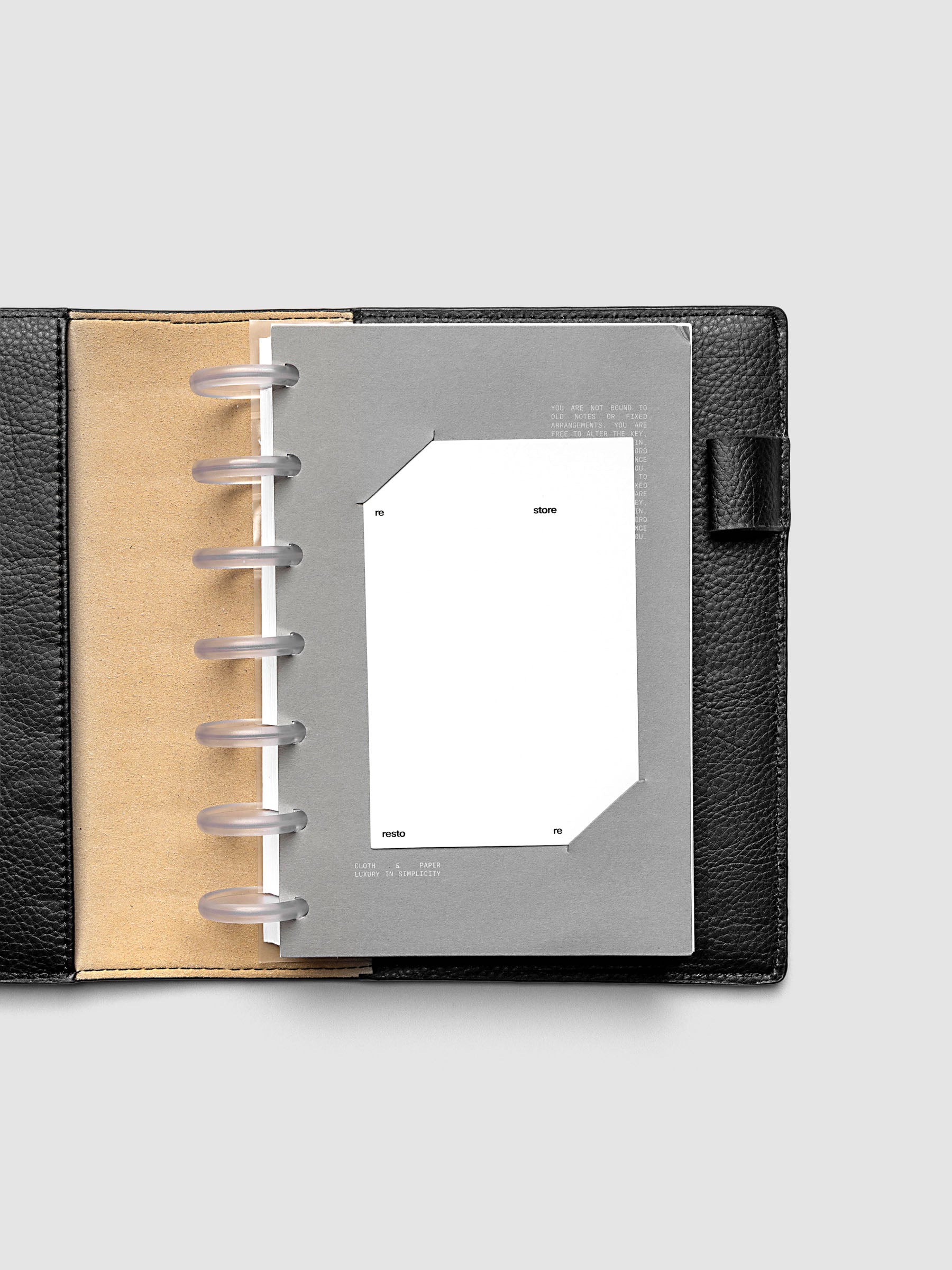 Grey cardstock planner dashboard with white plastic card inserted in slits with white printed text shown in size HP Mini in a discbound planner.