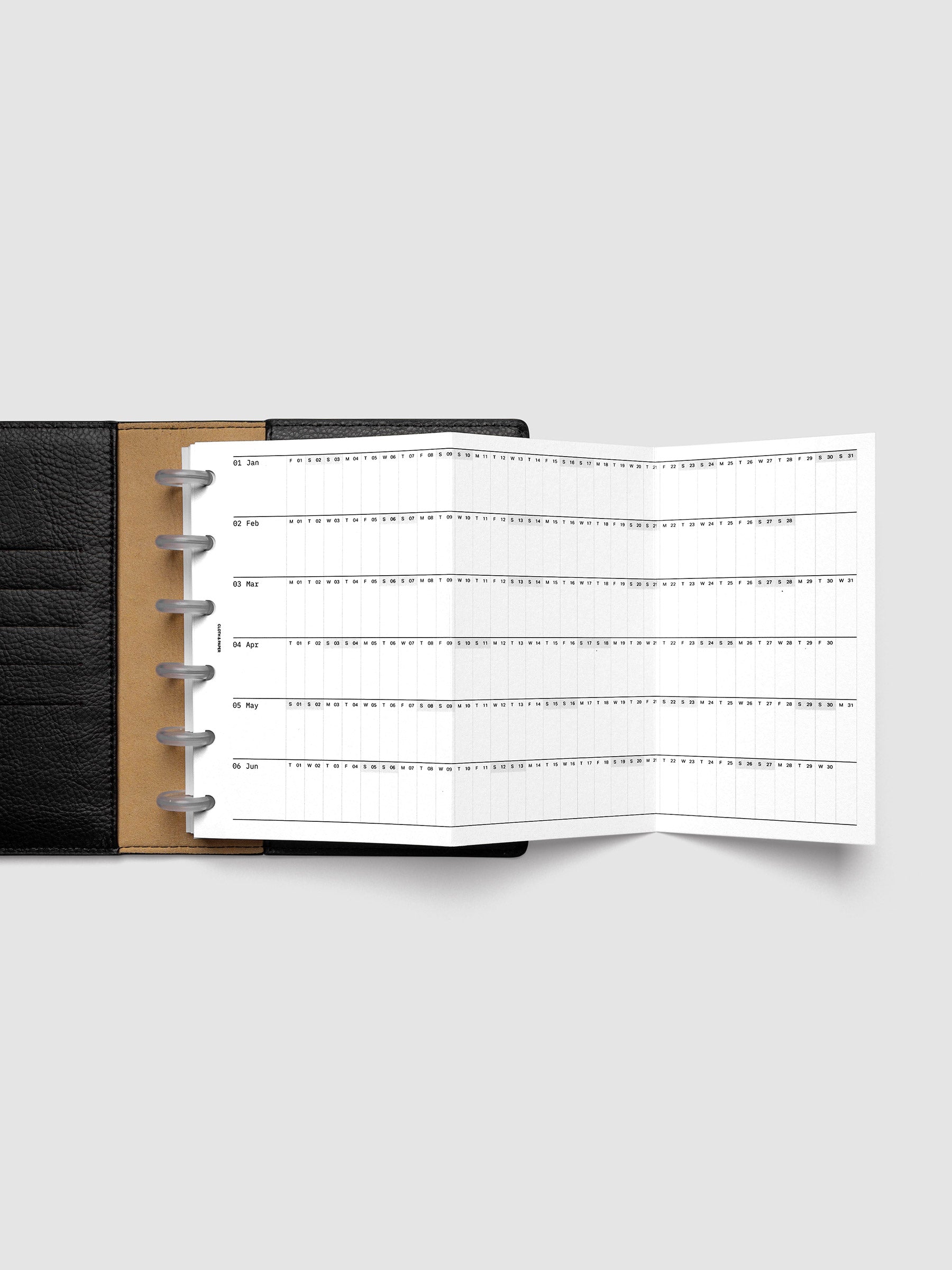 2027 Dated Fold Out Insert fully unfolded inside a CP Petite 6-Disc Punch discbound planner, showing six months of dated calendar boxes across one side.