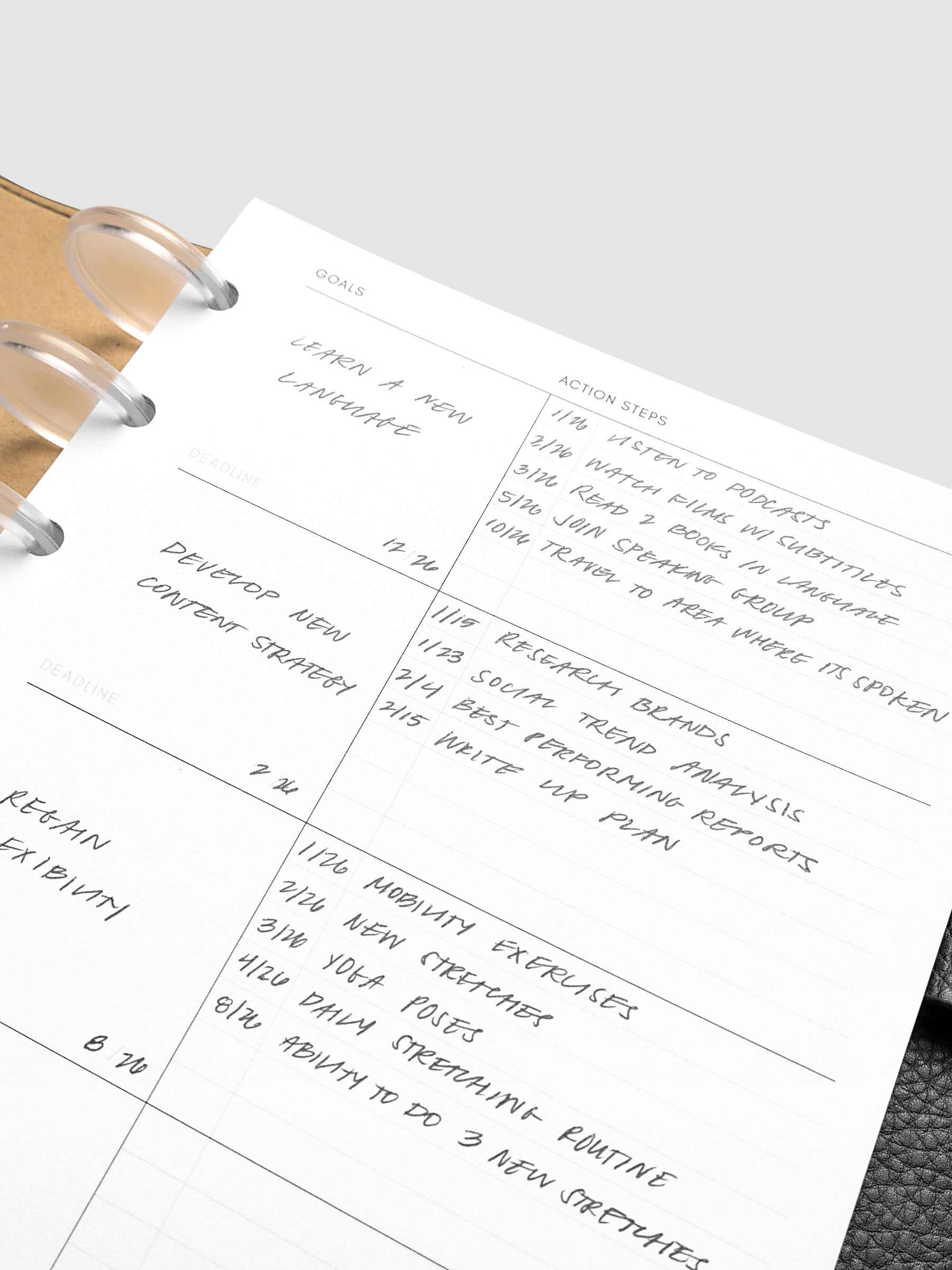 Open planner showing handwritten goals, deadlines, and action steps, including learning a new language and developing a content strategy. The page is neatly organized with clear headings and bullet points.