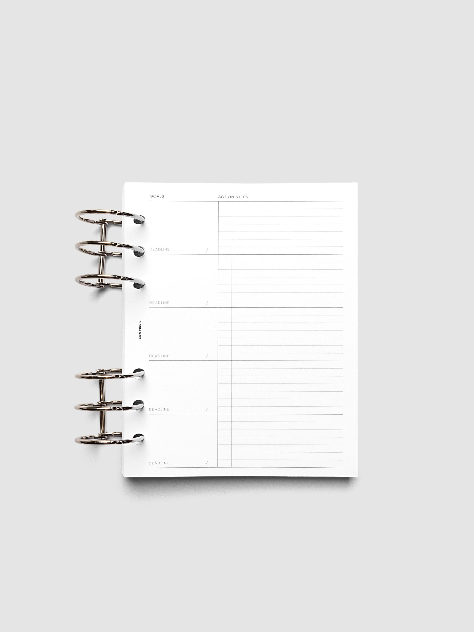 Open planner with blank goal-setting and action steps template on a white background. The page is divided into sections for goals, deadlines, and notes.