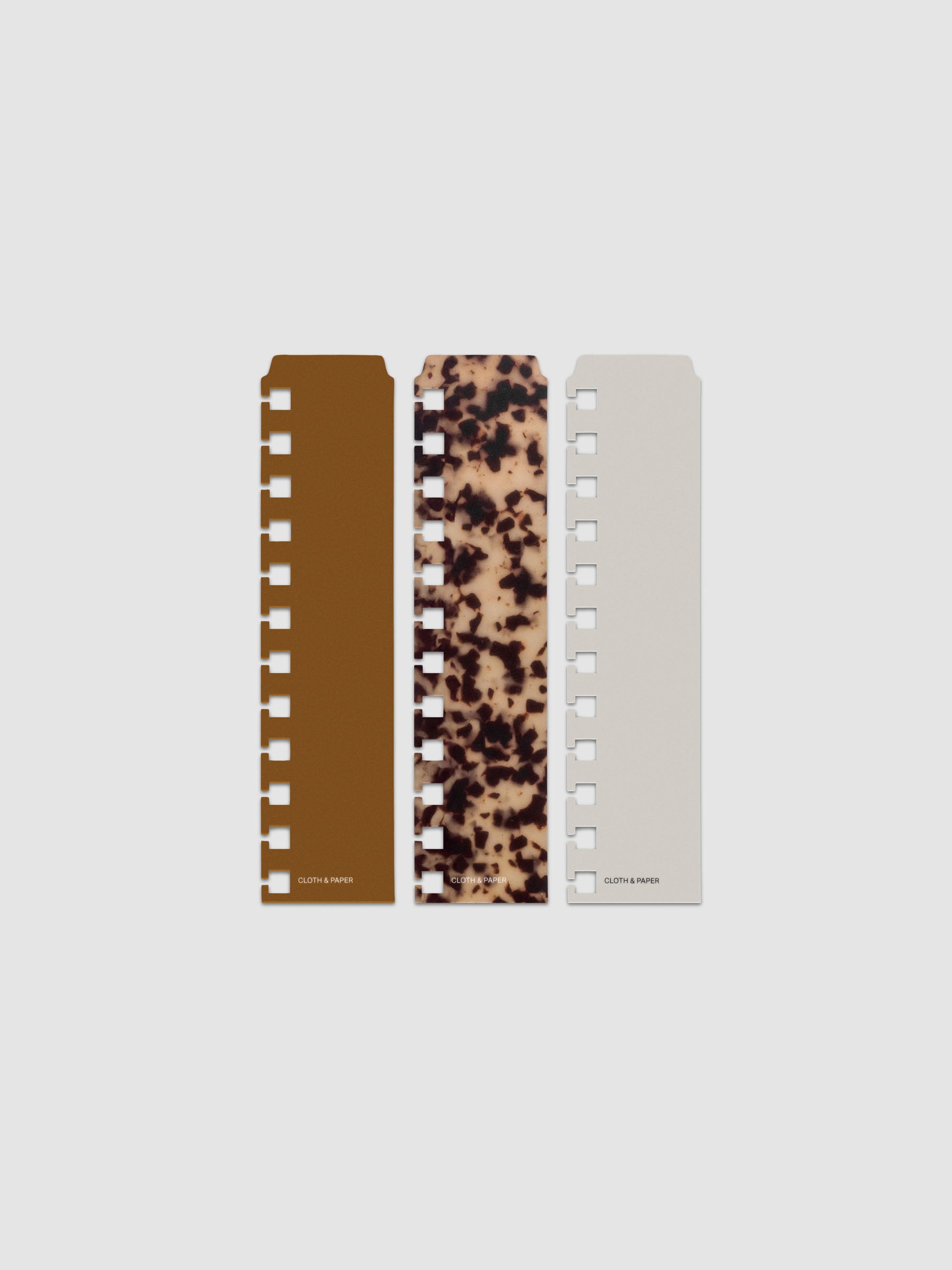 Narrow Page Marker Set Vol. 2, a set of 3 page markers for planners and notebooks shown in size CP Petite for spiral. Includes one tortoiseshell pattern, one solid brown, and one solid grey page marker.