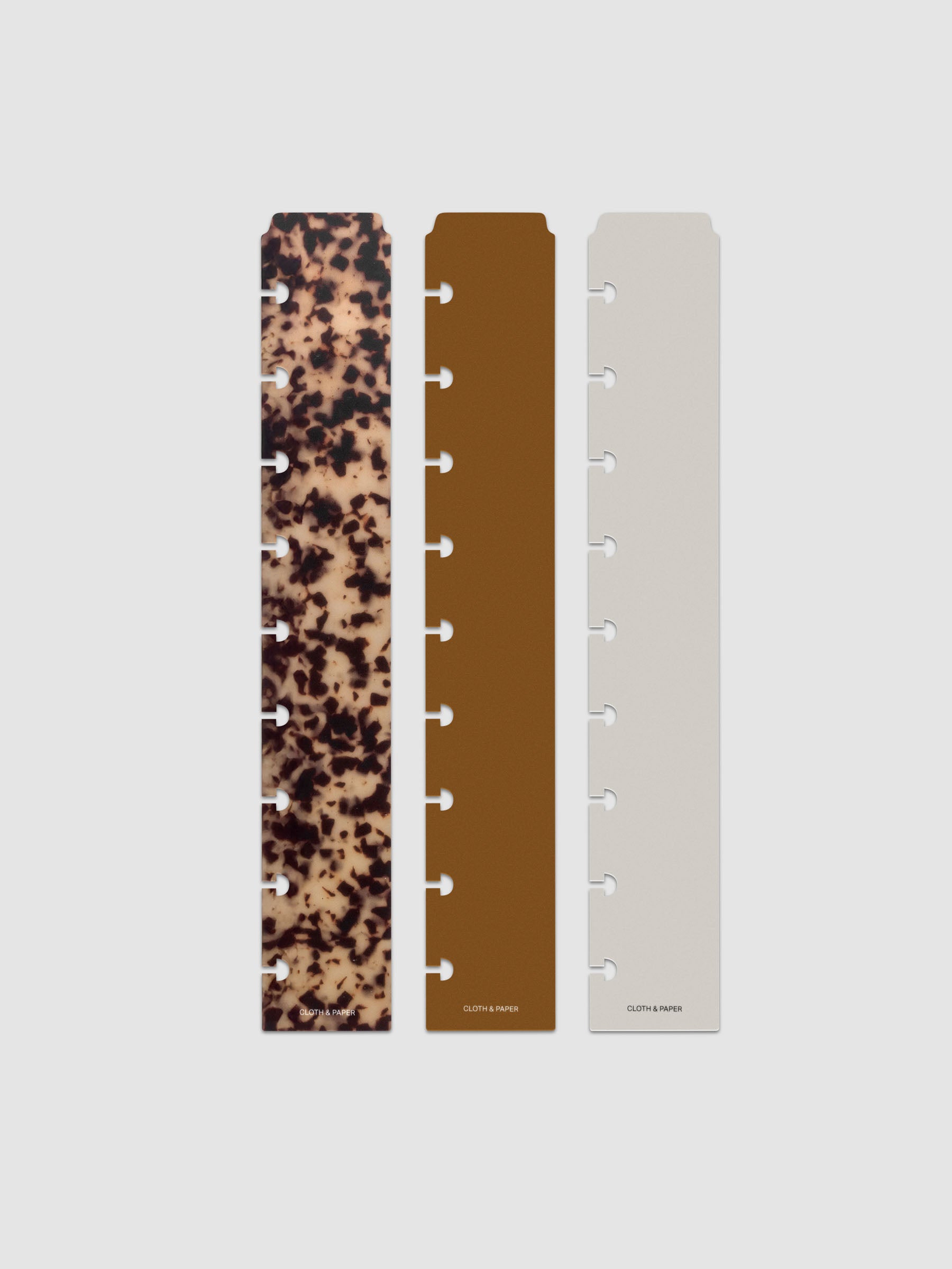 Narrow Page Marker Set Vol. 2, a set of 3 page markers for planners and notebooks shown in size HP Classic. Includes one tortoiseshell pattern, one solid brown, and one solid grey page marker.