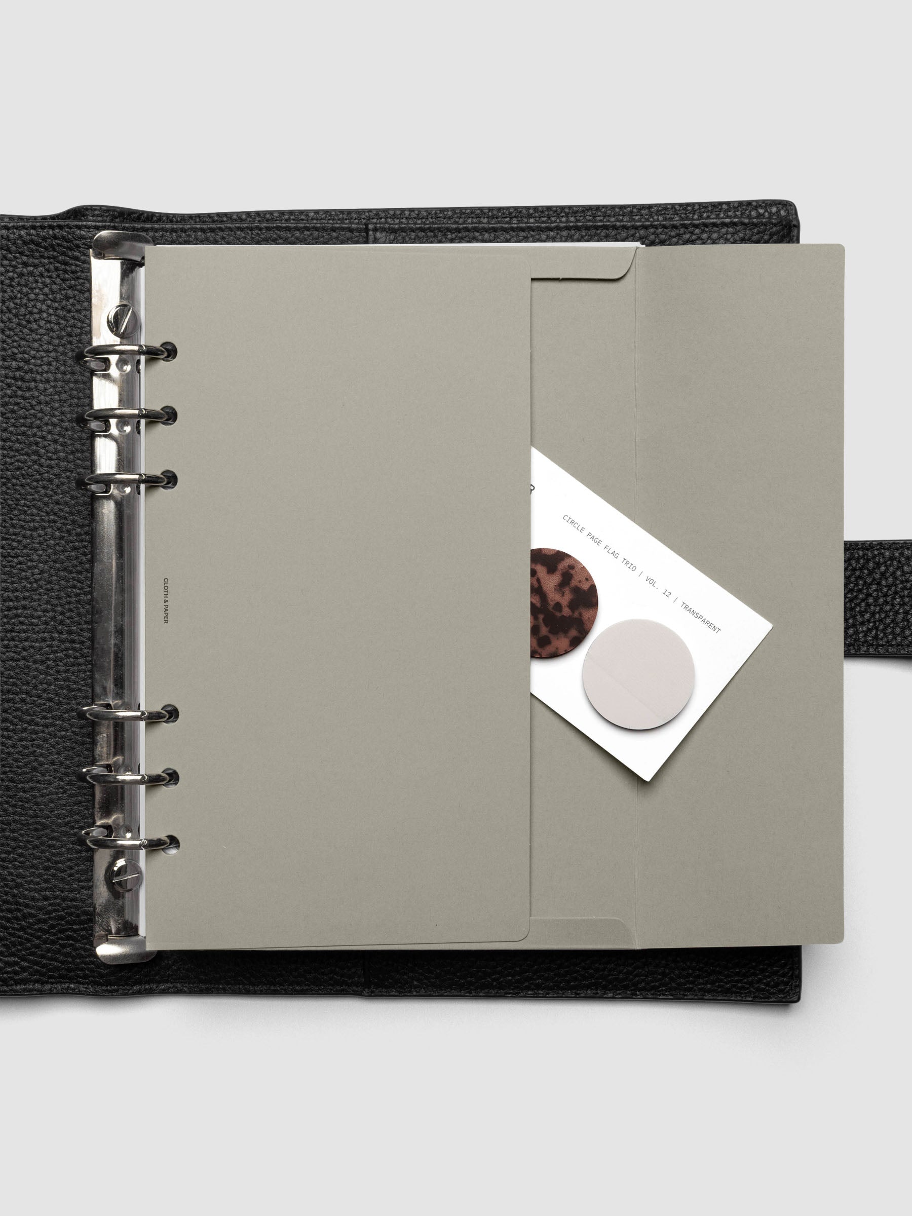 Beige Envelope Storage Holder shown inside a black, leather A5 agenda with page flags inside.