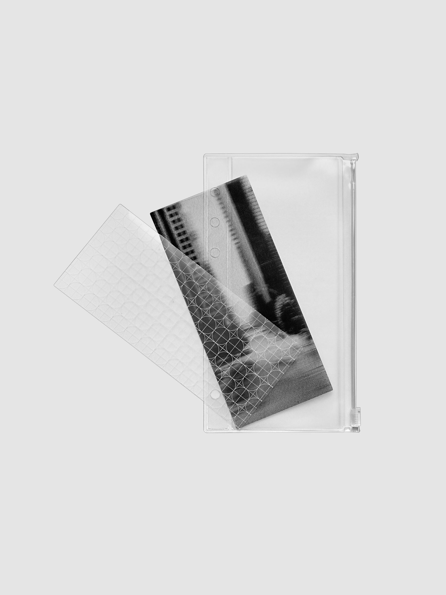 One transparent graph overlay, one black and clear abstract photo overlay, and one clear pre-punched zippered pouch for planners. Shown in size Personal.