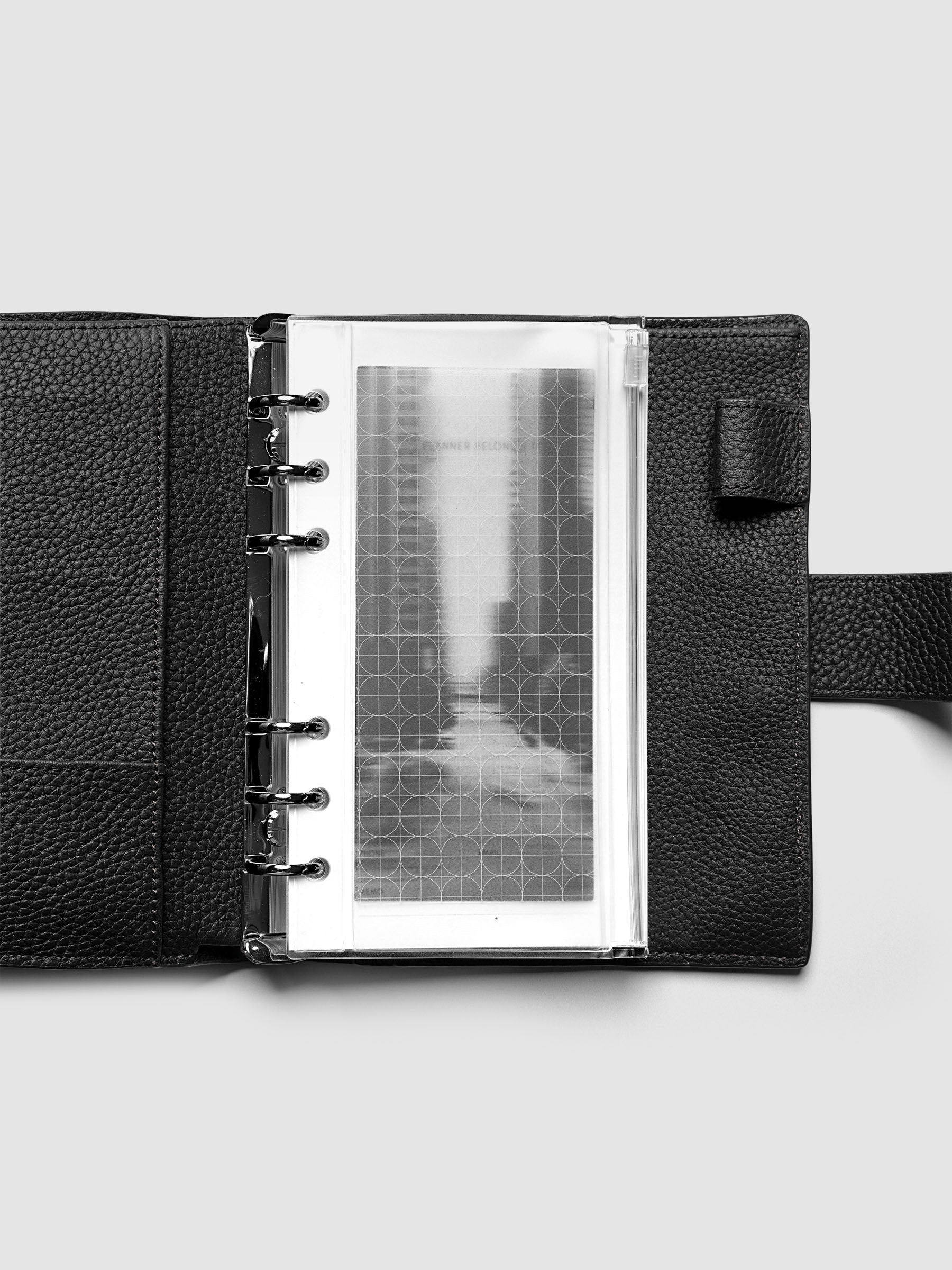 Side zipper transparent storage pouch for planners with decorative inner graph and photograph layers shown in a Personal planner agenda cover.