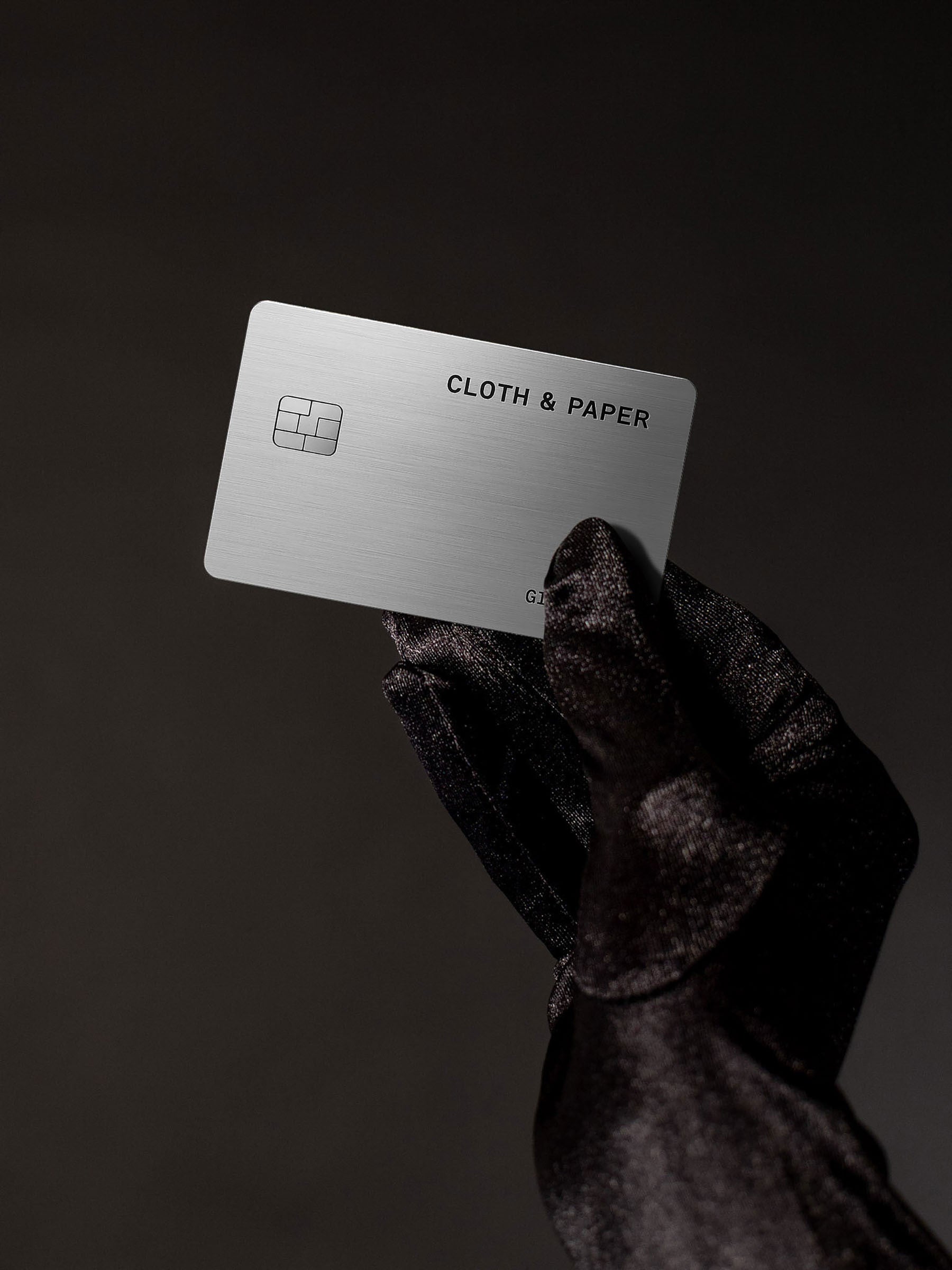 Gloved hand holding a C&P Gift card against a dark backdrop.