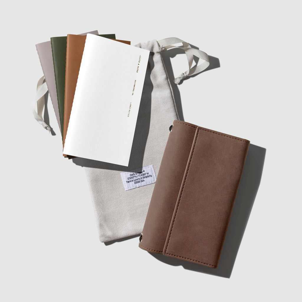 Cover with four notebooks and dust bag displayed on a neutral background.