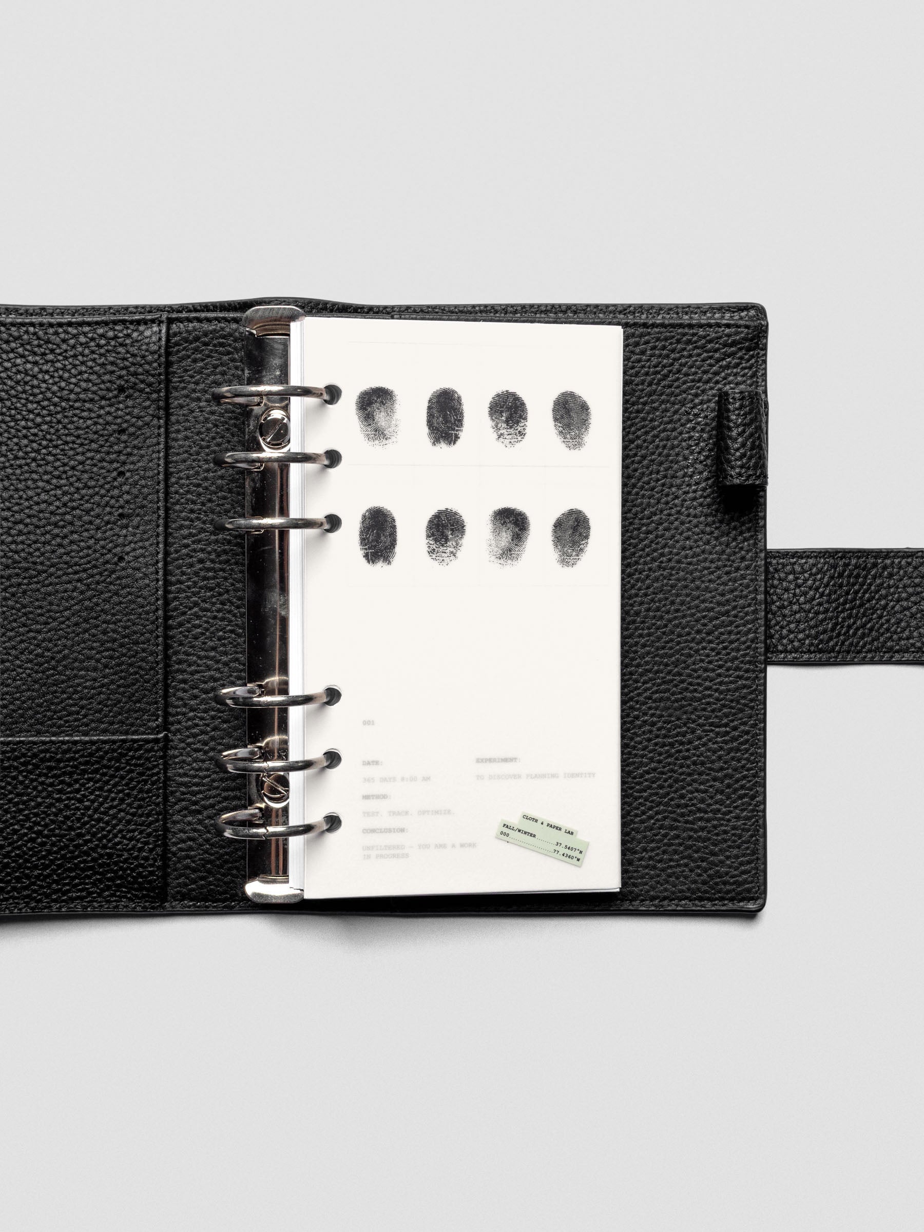 Two layered Personal sized planner dashboards, one semi-transparent, one matte, featuring a fingerprint design shown inside a leather folio.