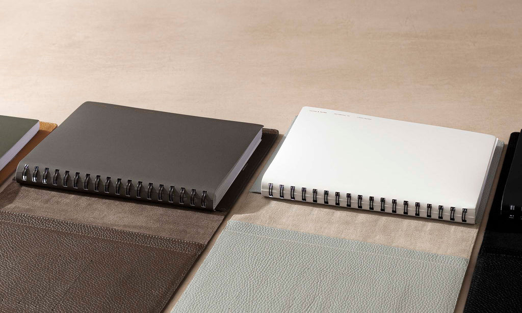Heirloom Leather Folios in HP Classic are opened and arranged on a desk against a light brown background.  Inside the Folios are España Spiral Notebooks in HP Classic.