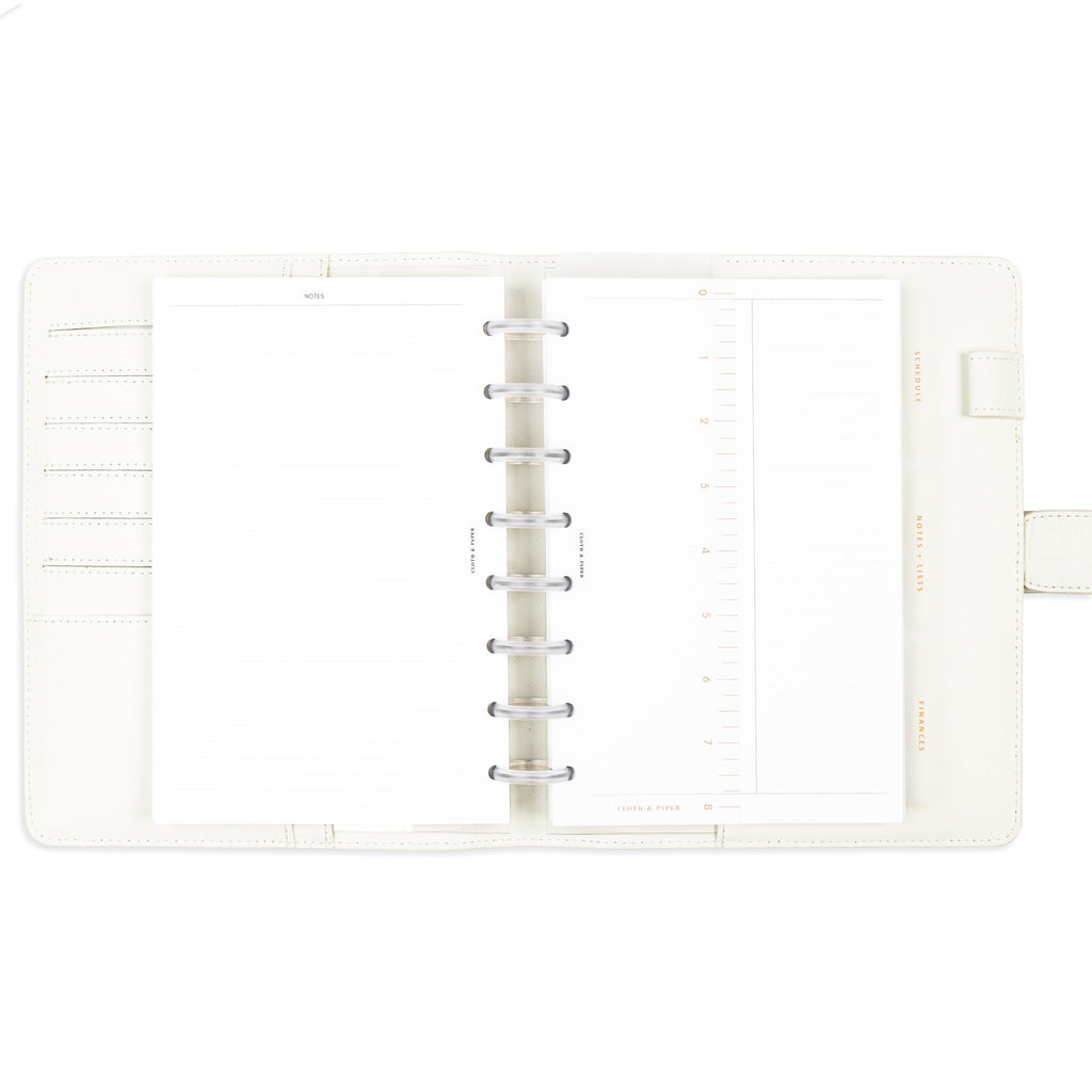 Dividers with fossil text in use inside a discbound planner system housed inside a white leather cover.
