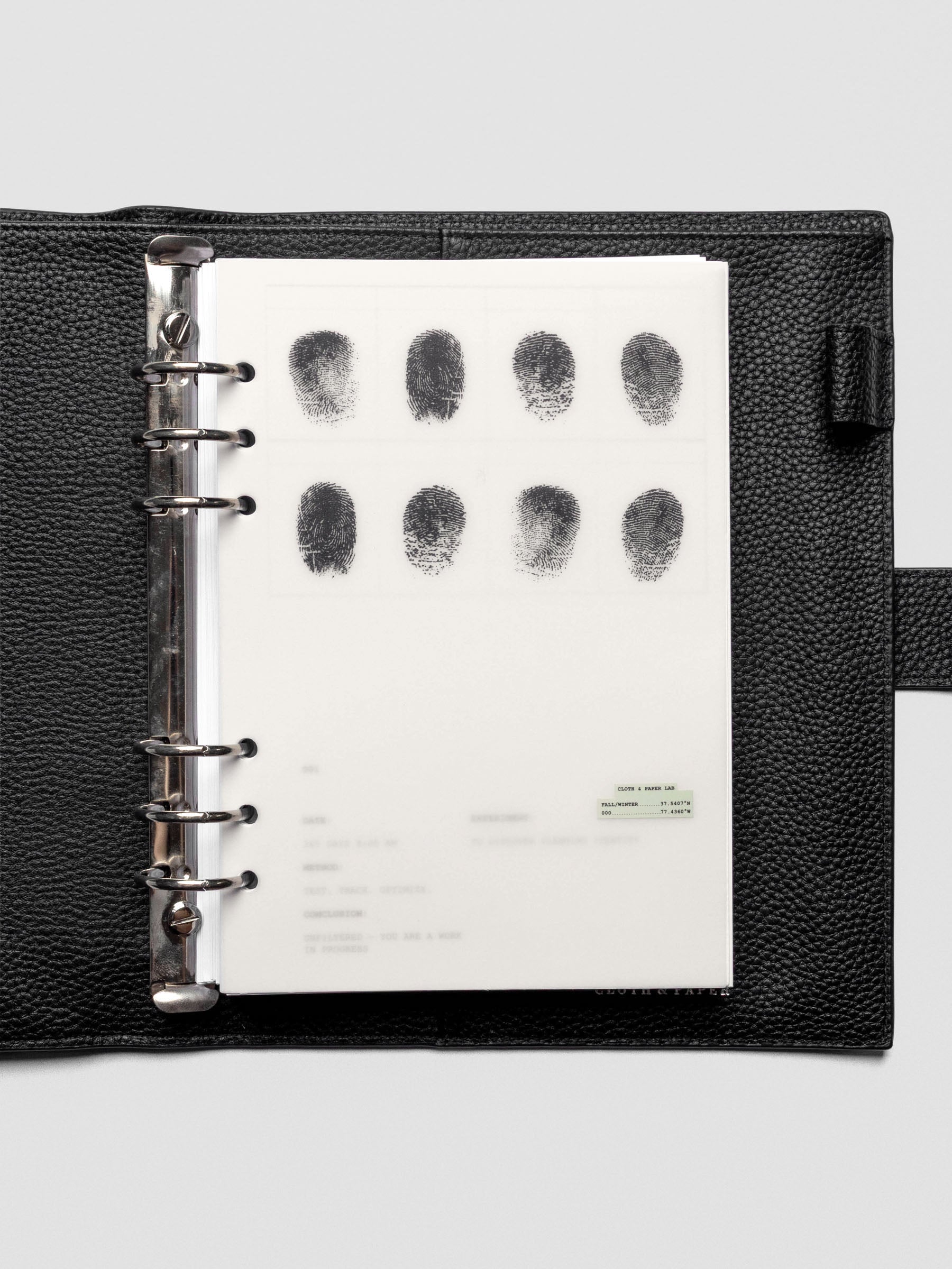 Two layered A5 size planner dashboards, one semi-transparent, one matte, featuring a fingerprint design shown inside a leather folio.