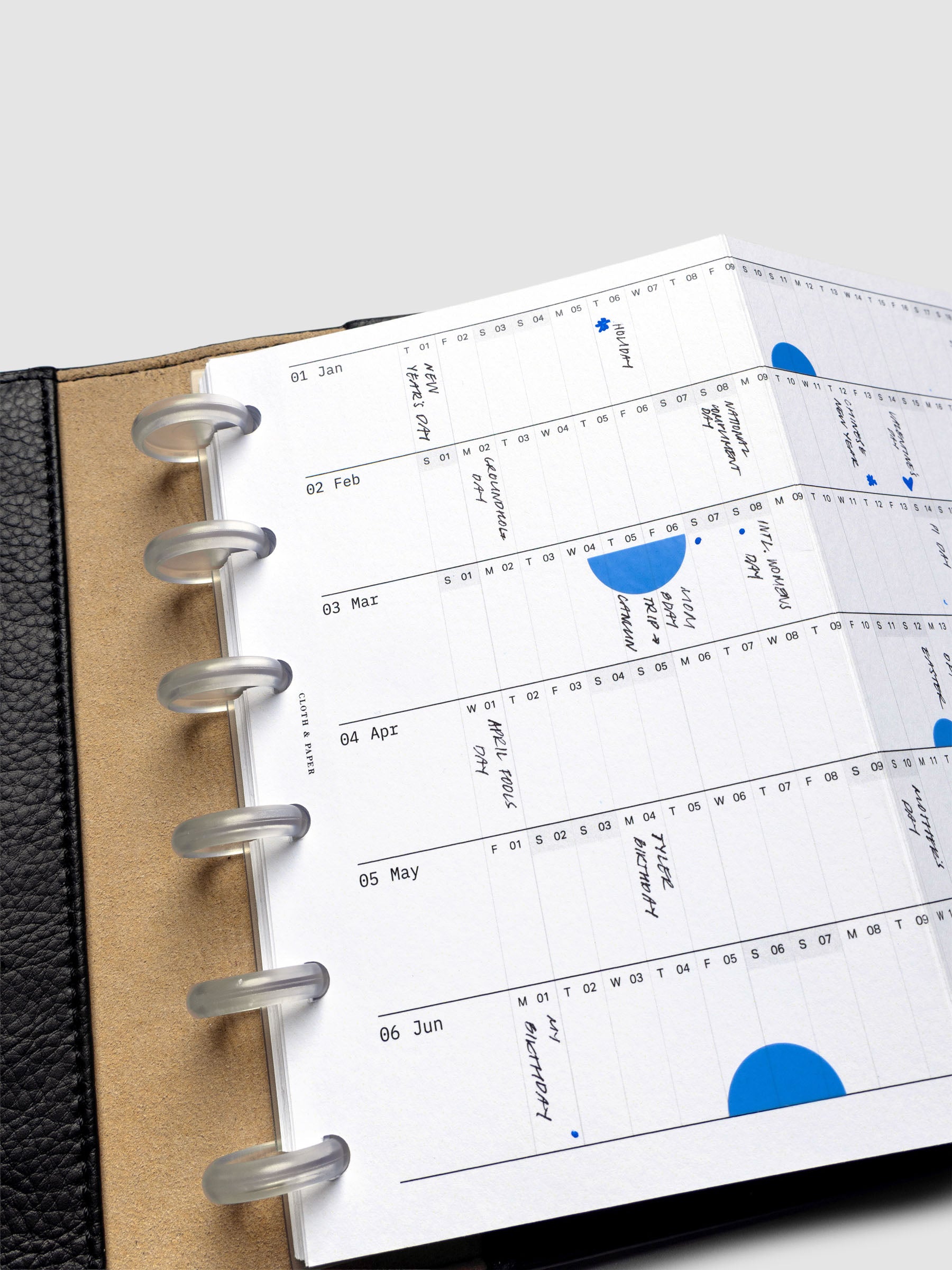 2026 Yearly Fold Out Planner Insert in size CP Petite shown un-folded, in use, in a black leather folio cover.