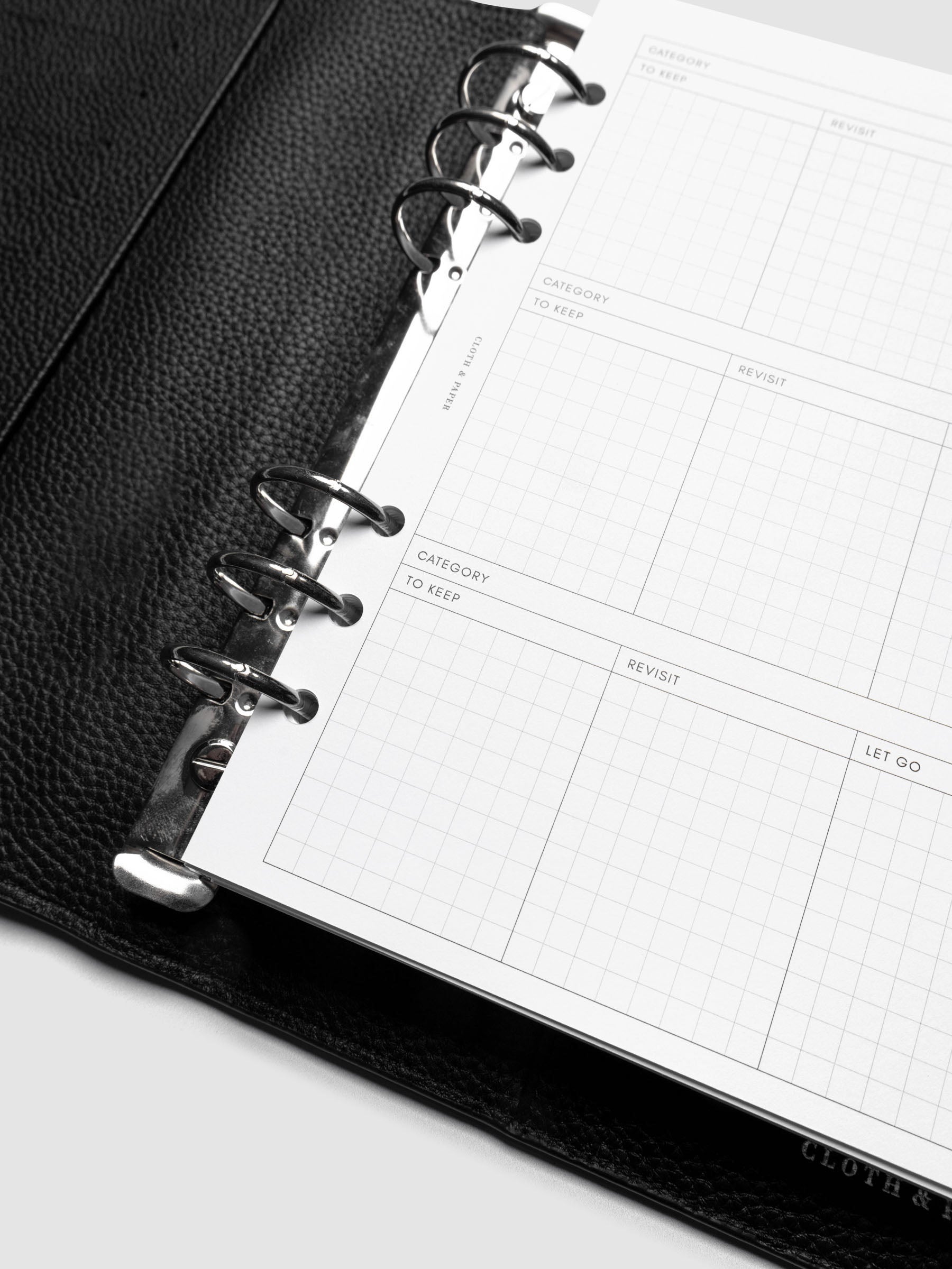 Close up of Declutter Planner Inserts in size A5 shown ring bound in a black leather agenda.