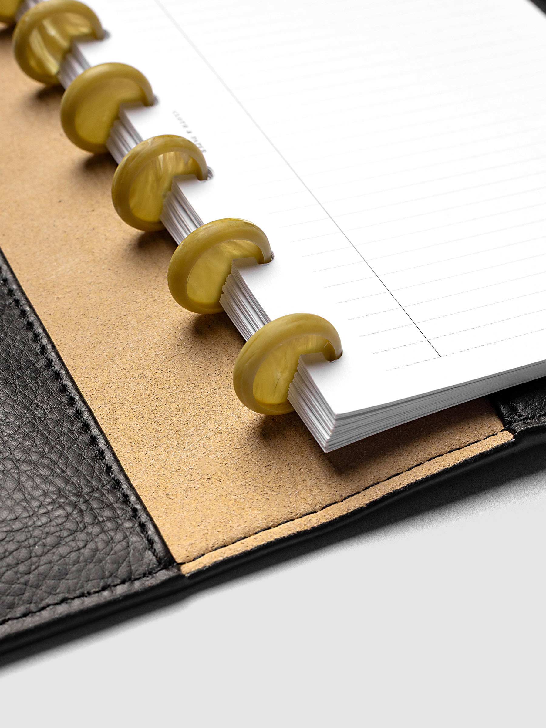 Close-up of Carrara Verde 0.75" planner discs in a discbound planner, highlighting the marbled green finish and disc construction