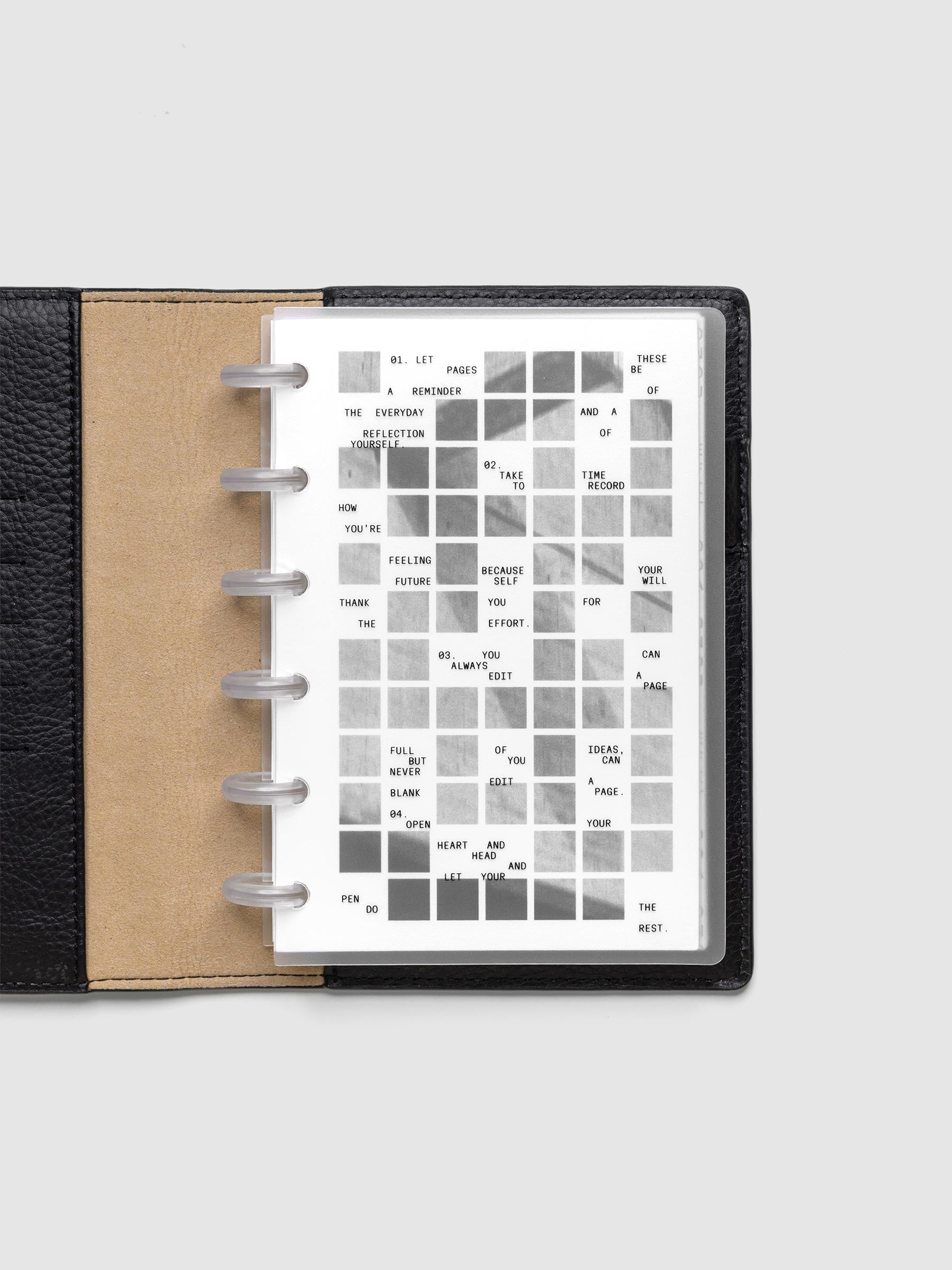 Clear planner cover with black printed text paired with a photographic black and white dashboard. Shown pre-punched for discbound planners in the size CP Petite in a black folio.