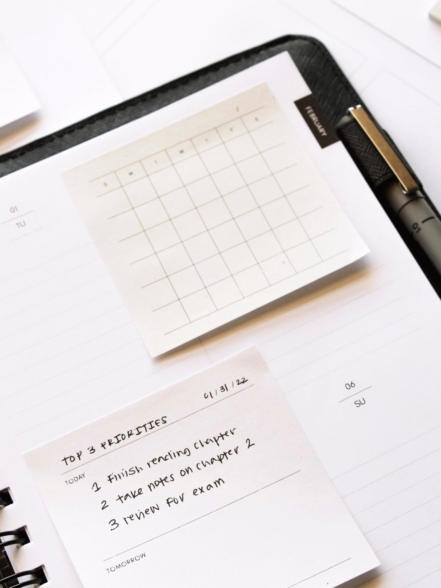 Sticky notes printed using printable in use inside a spiral bound planner. Spiral bound planner is inside a leather agenda cover with Uni Pin inside planner's pen loop.