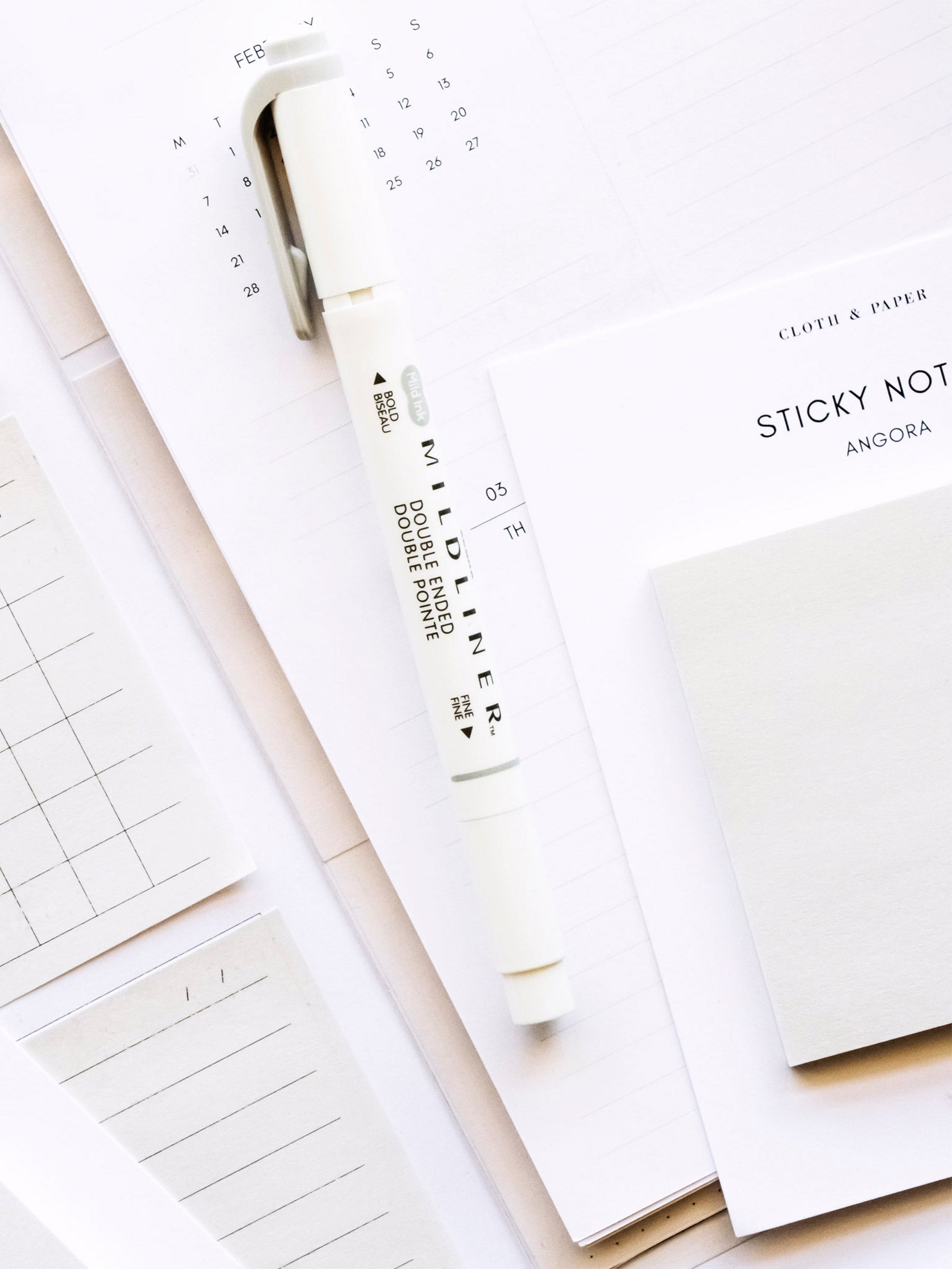 Sticky note pads, planner page, Zebra Mildliner Highlighter, and printed sticky notes layered together on a table.