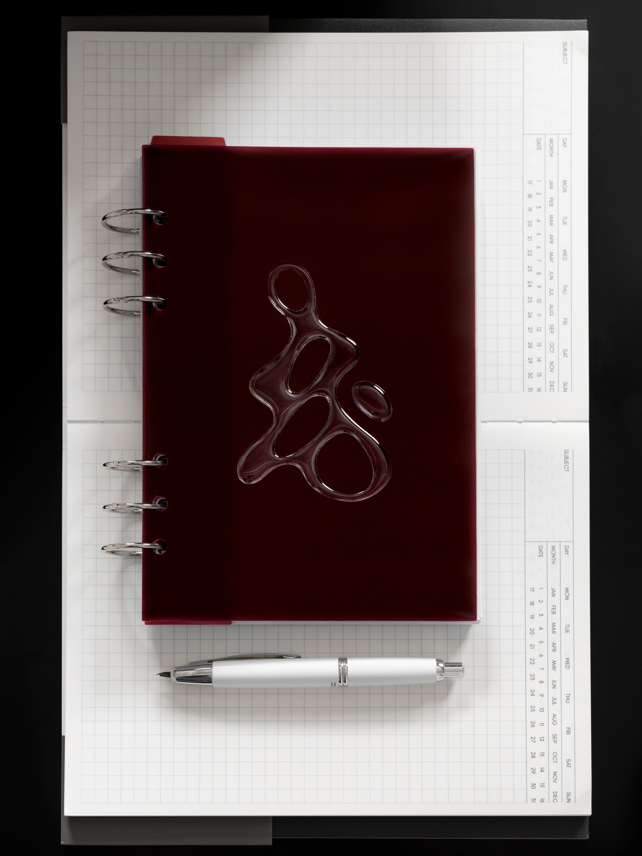 Gloss Form Planner Dashboard | Bordeaux shown ringbound in size A5 on an open notebook.