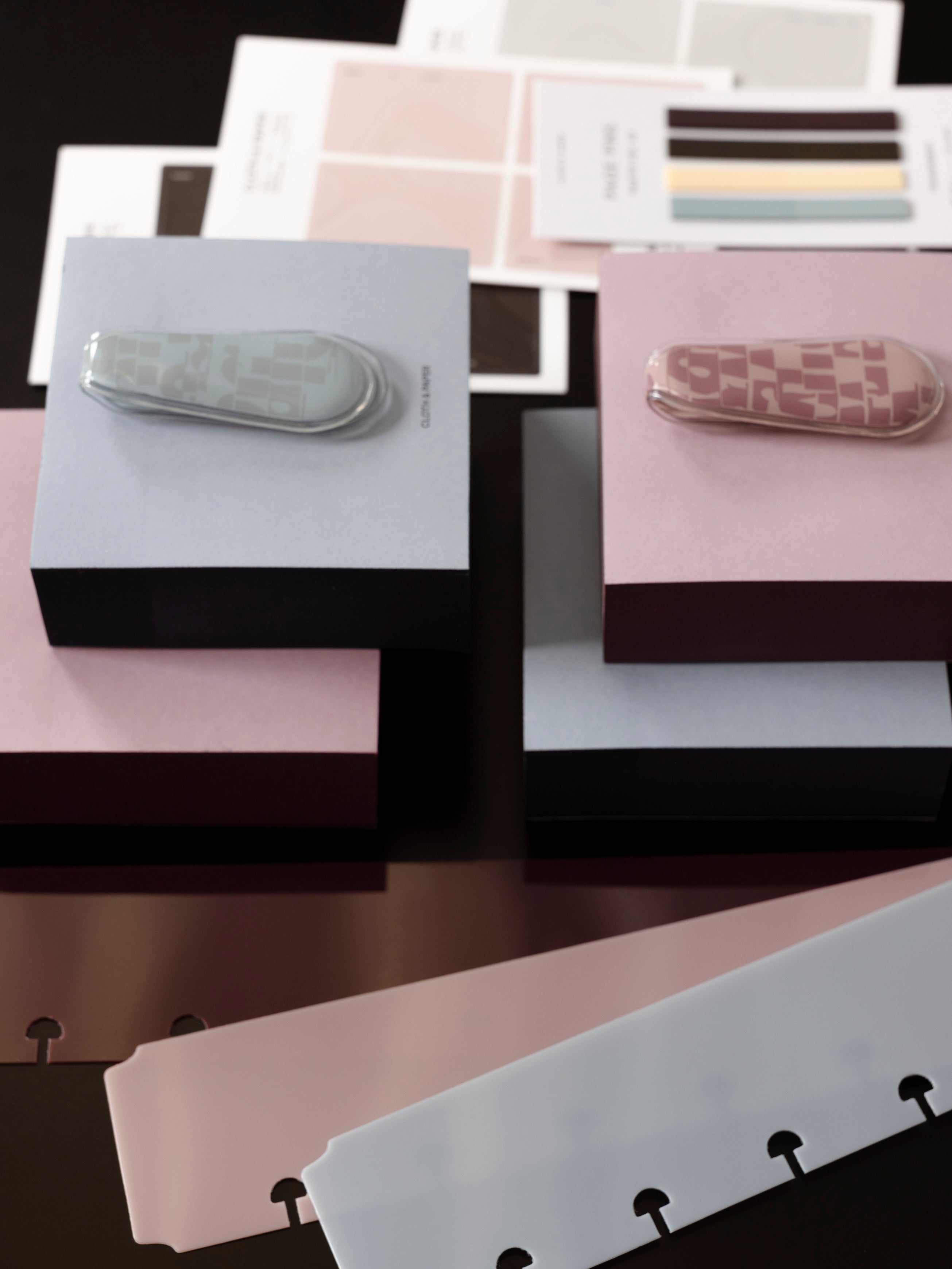 One blue and one pink magnetic bookmark laying flat on top of color block sticky notes.