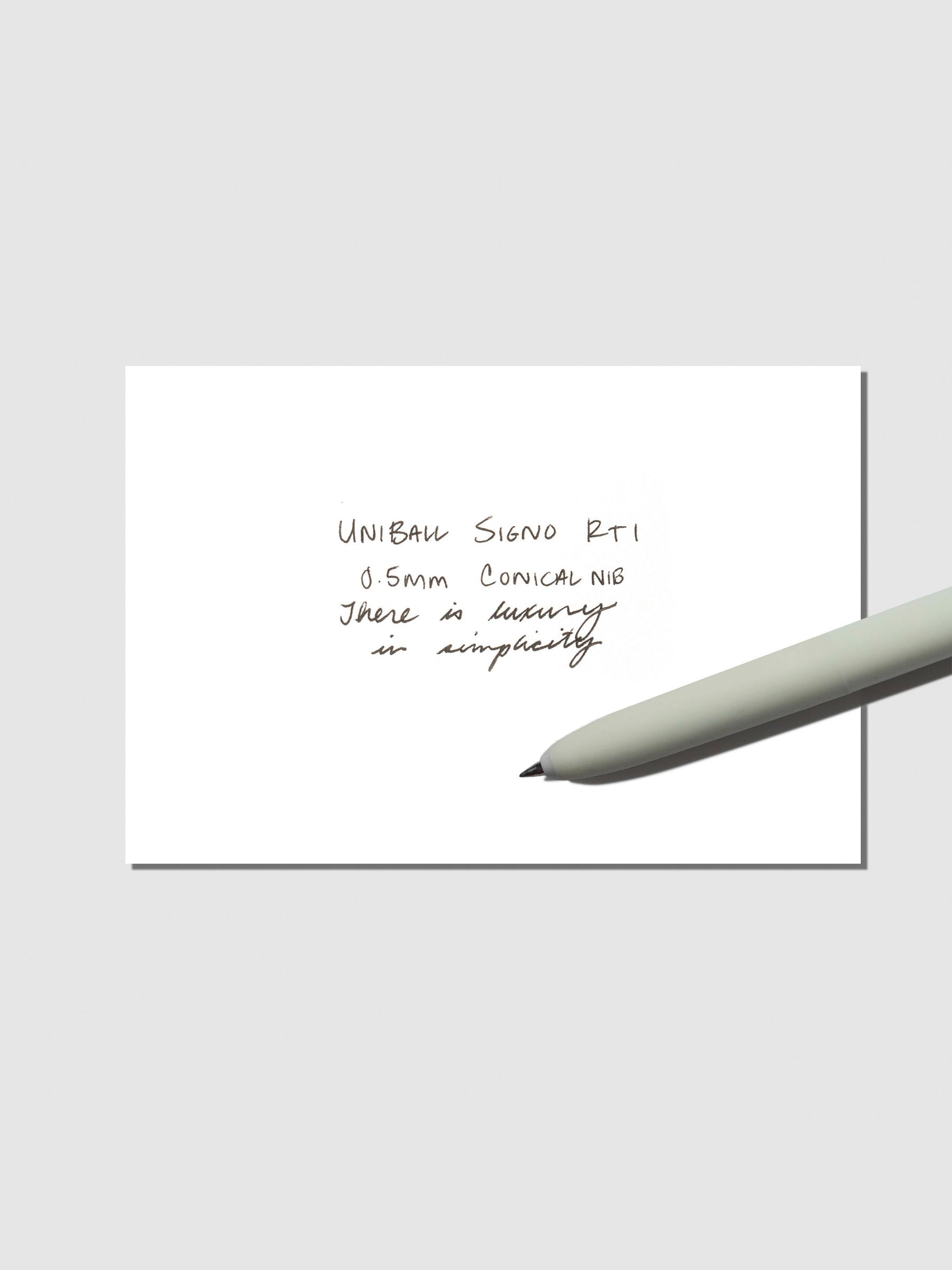 Uni Ball Signo in Opal Green displayed with writing sample on a neutral background.