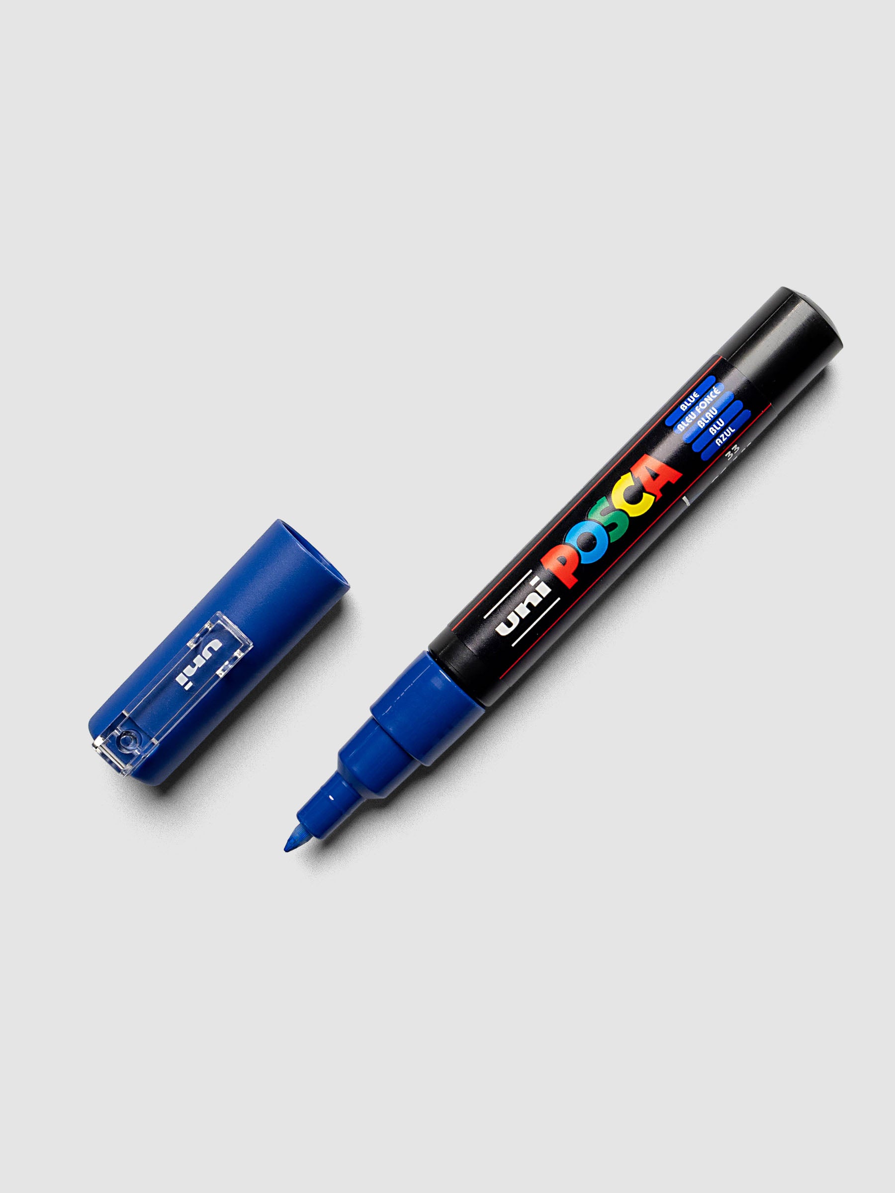 Black barrel marker with blue tip and ink shown with cap off against a light grey background.