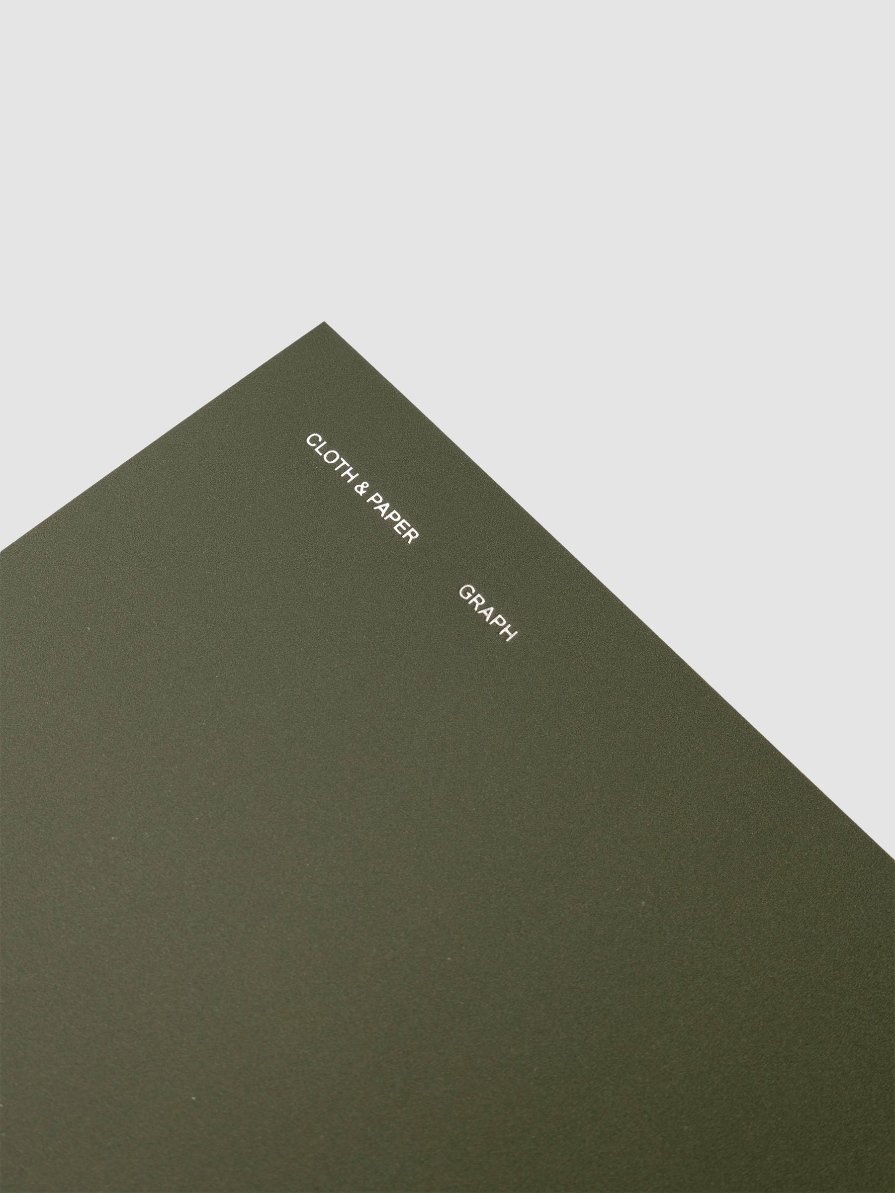 Spiral Notebook in size A5 and color Olive green with graph note interior pages showing a close up of the silver foil details on the soft touch cover.