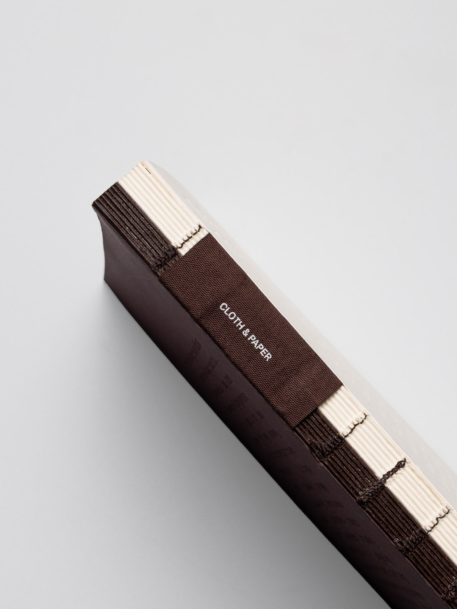 The spine of the Common Thread Notebook showing a fabric tag and the split paper color of the notebook.