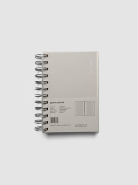 Spiral Notebook in size CP Petite and color Ash with Lined Note interior pages shown closed from the front with belly band.