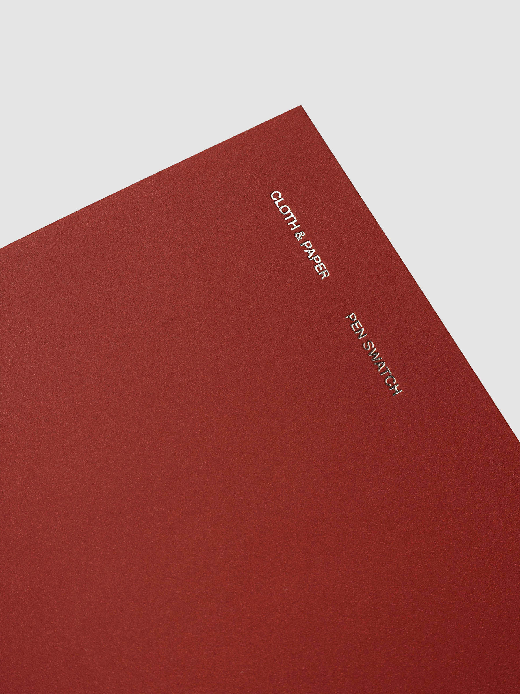 Travel Notebook Pen Swatch Pocket Plus in Merlot, close up angled corner of red cover with silver foil text