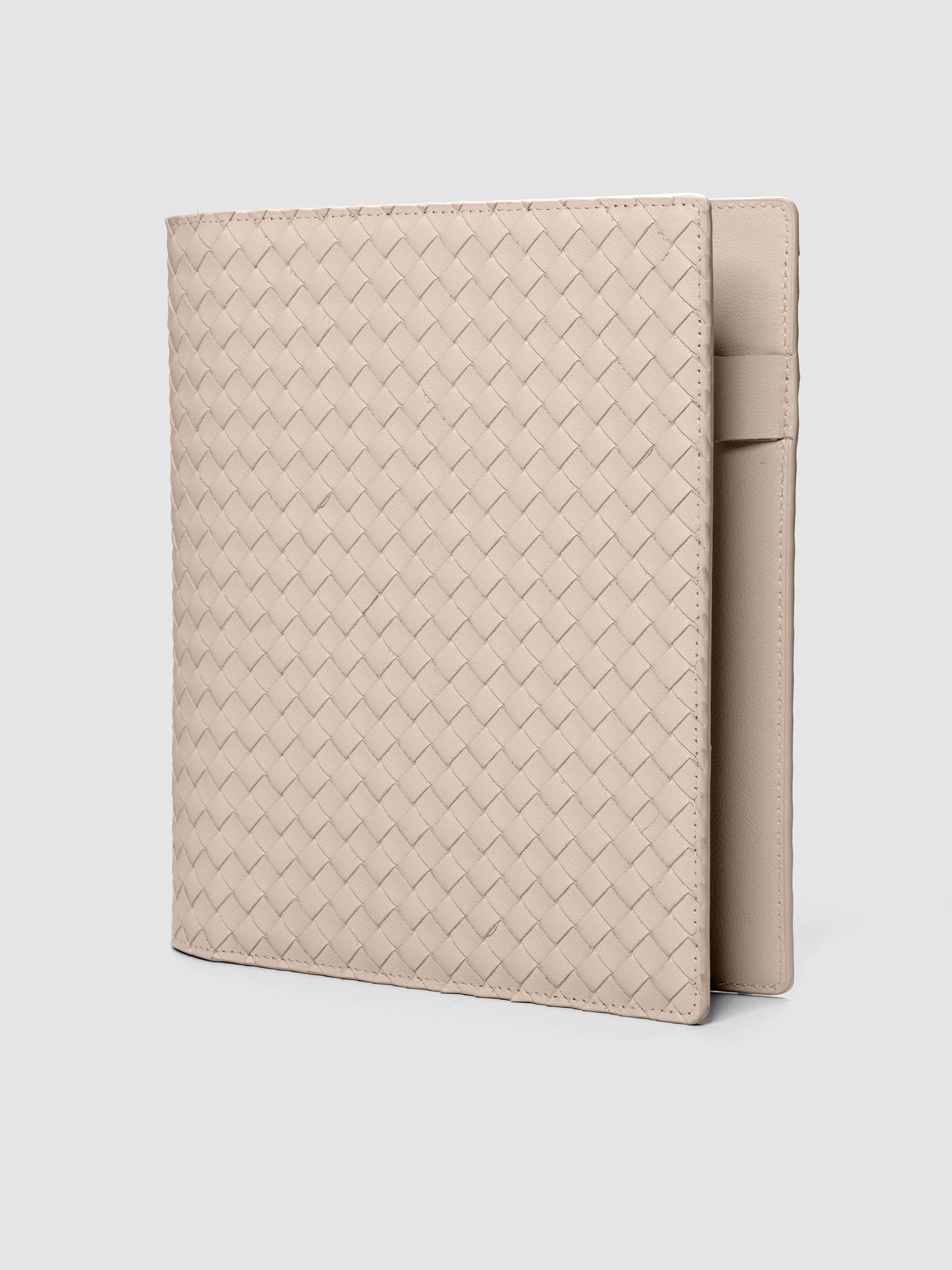 Beige woven leather planner cover shown standing at an angle.