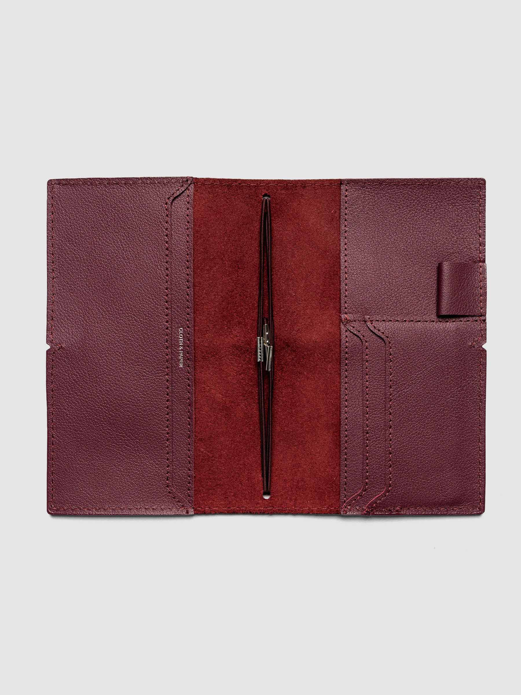 Deep red leather travel notebook cover in size Pocket Plus shown open with interior pockes and elastic bands.