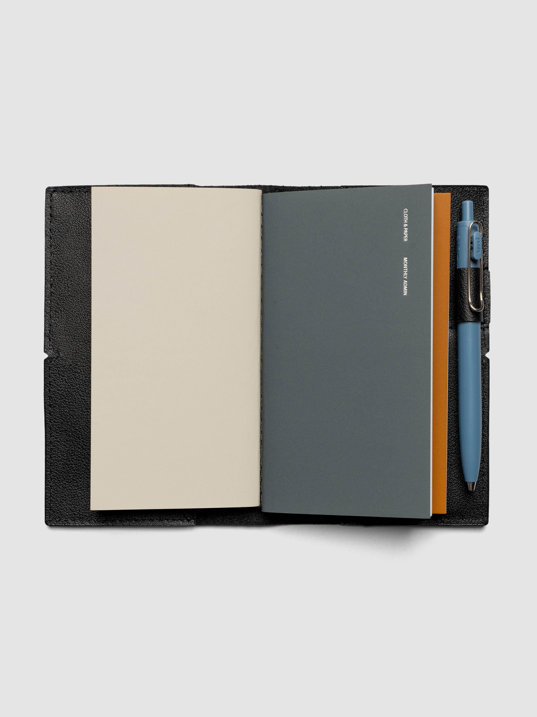Black leather travel notebook cover in size Pocket Plus shown open with a pen in the pen loop.