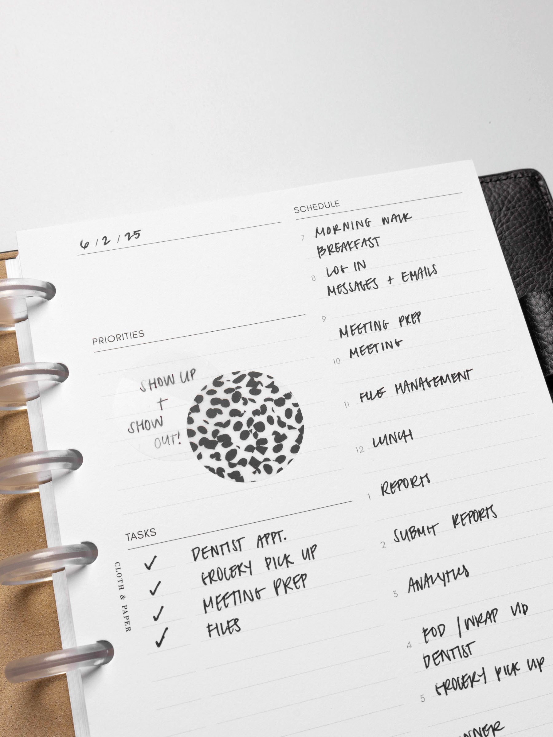 Closeup of inserts in use inside a leather planner. They are filled out with sample text and have been decorated with Spotlight stickers, Strips planner stickers, and a transparent Circle Page Flag.