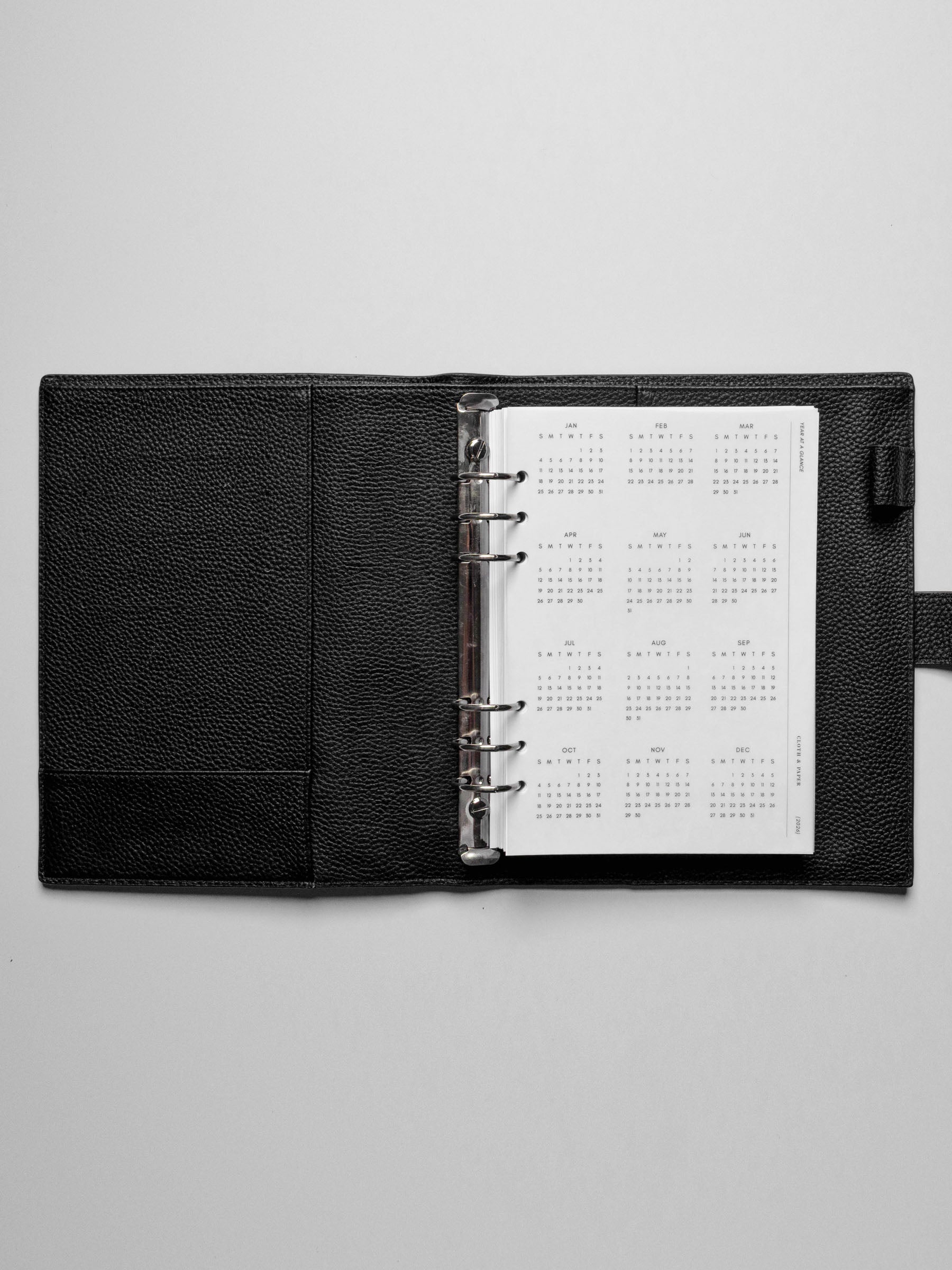 The 2026 Year At A Glance Planner Dashboard in a black leather ring-bound planner.