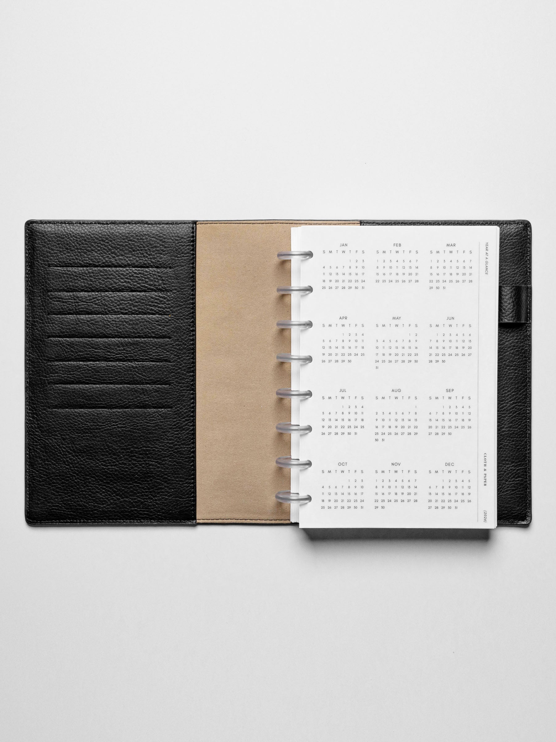 The 2026 Year At A Glance Planner Dashboard in a black leather disc-bound planner.
