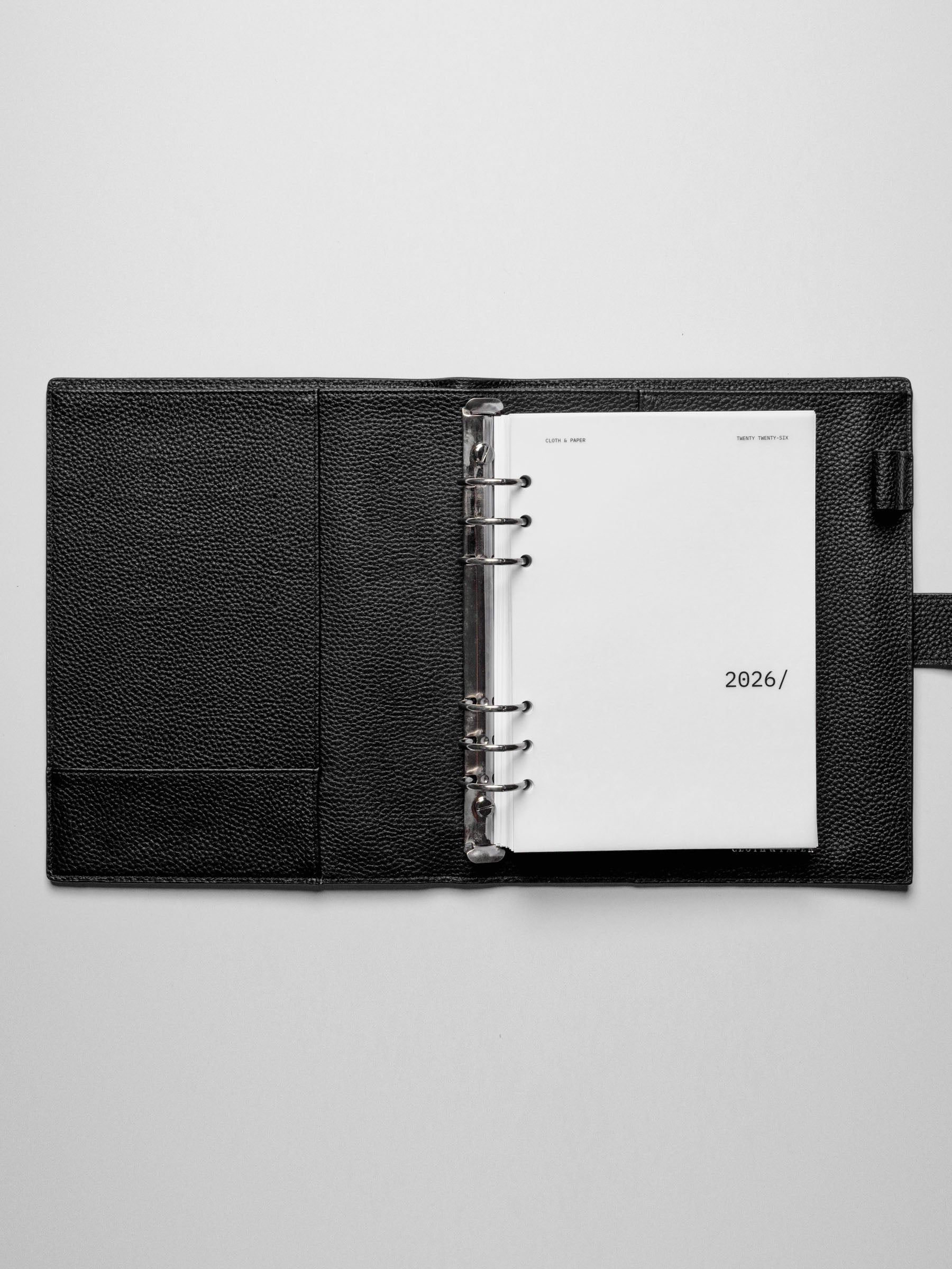 Image shows the 2026 front cover used in a black leather A5 ring-bound planner.