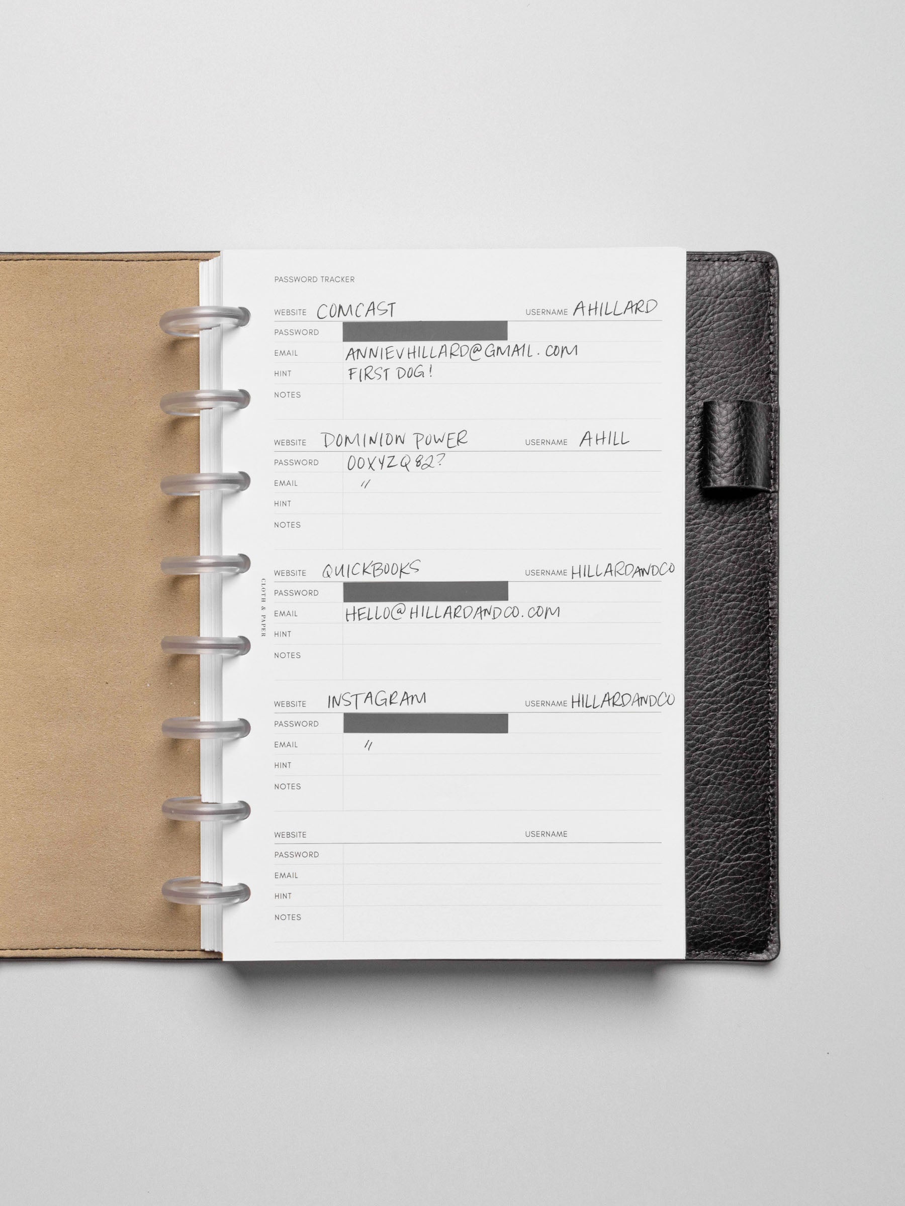 Insert in use inside a black leather planner. Page pins have been used to block out the password field, and the rest of the insert is filled out in pen.