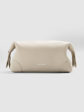 Folded Form Pouch in warm beige pebbled leather, three-quarter view, snapped closed with silver foil Cloth & Paper logo visible on exterior