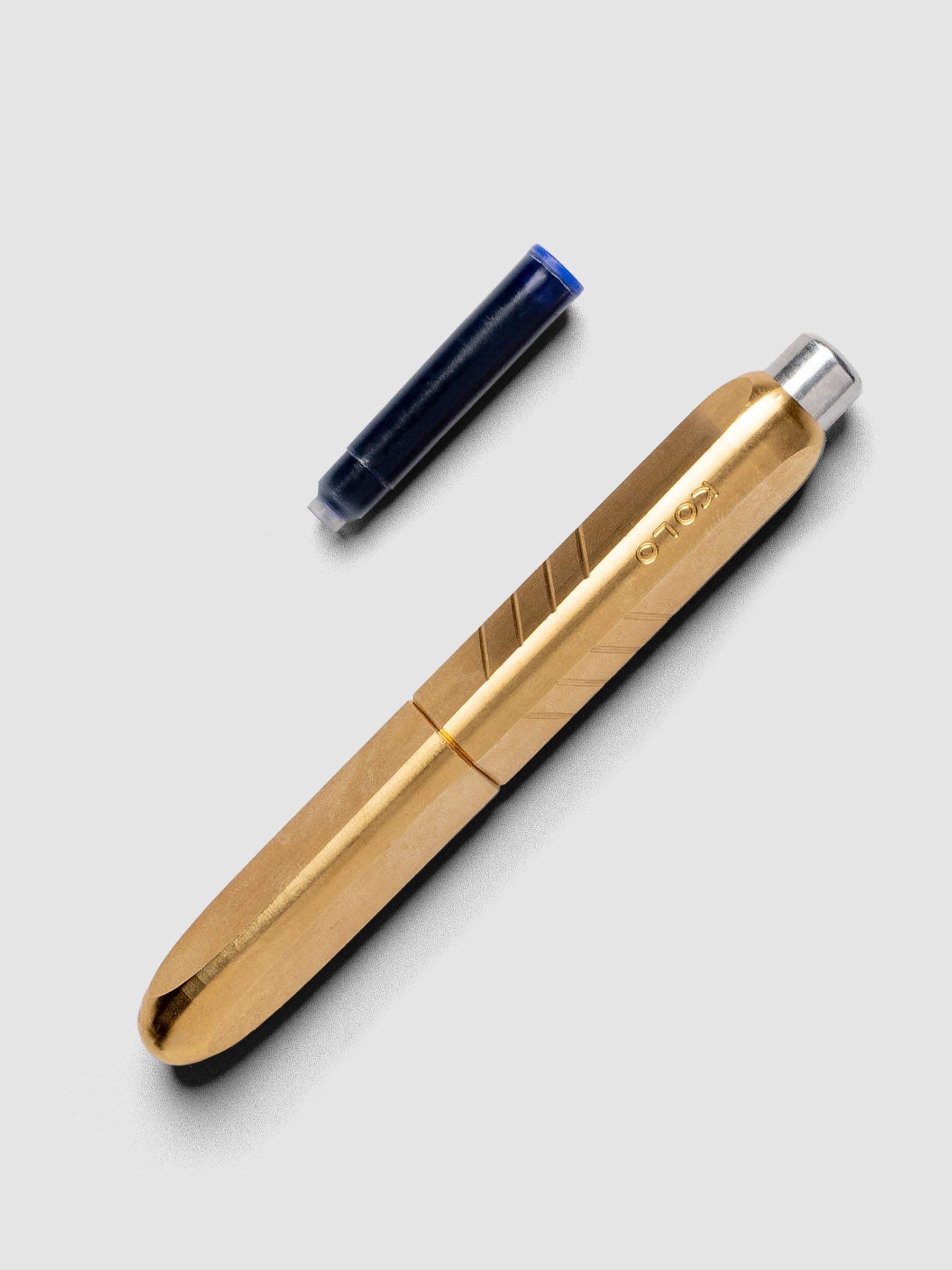 Kolo Tino Fountain Pen in the color Raw Brass, shown cap on with ink cartridge resting beside pen.