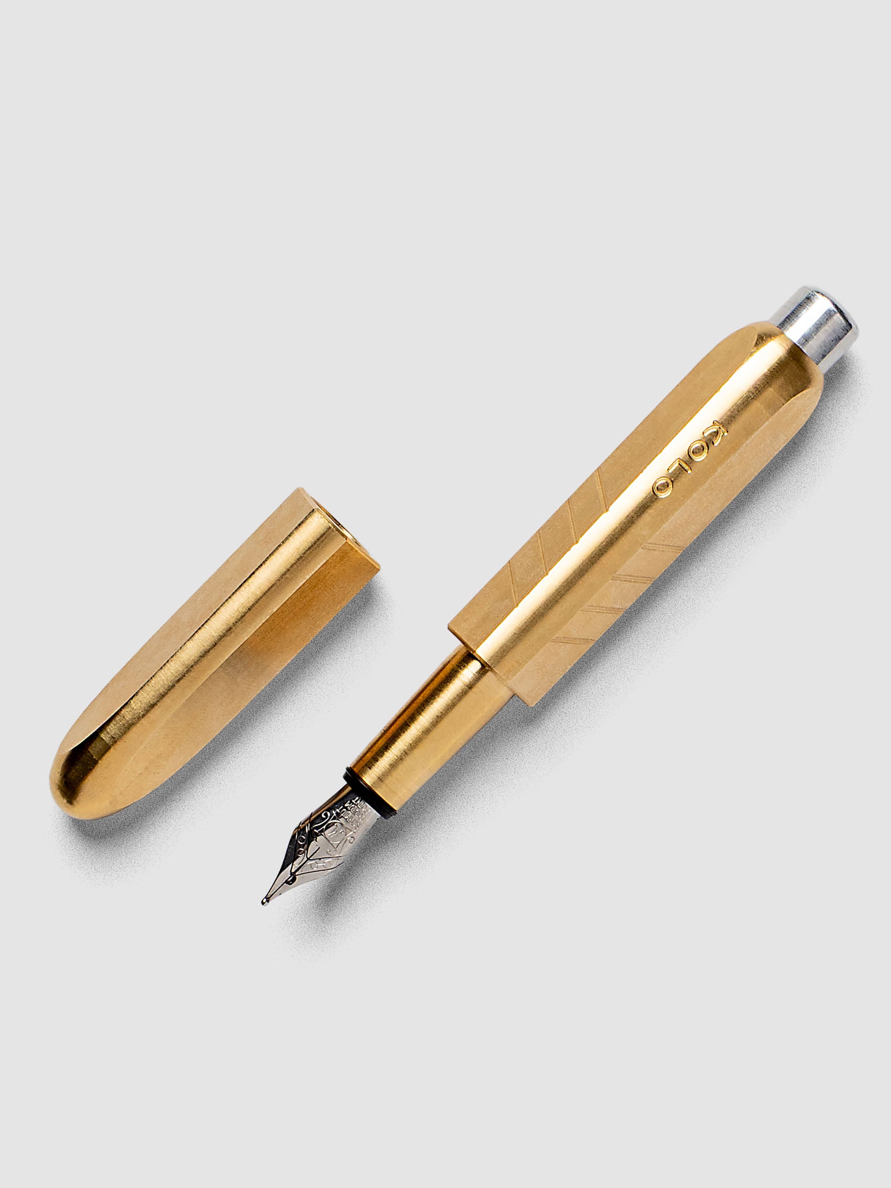 Kolo Tino Fountain Pen in the color Raw Brass, a warm toned metal barrel with silver accents and a silver medium nib shown with cap off.