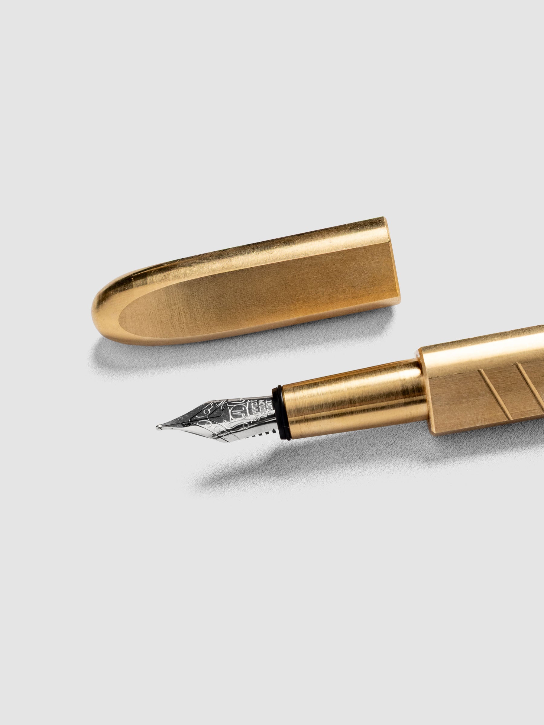 Kolo Tino Fountain Pen in the color Raw Brass, a warm toned metal barrel with silver accents and a silver medium nib shown with cap off.