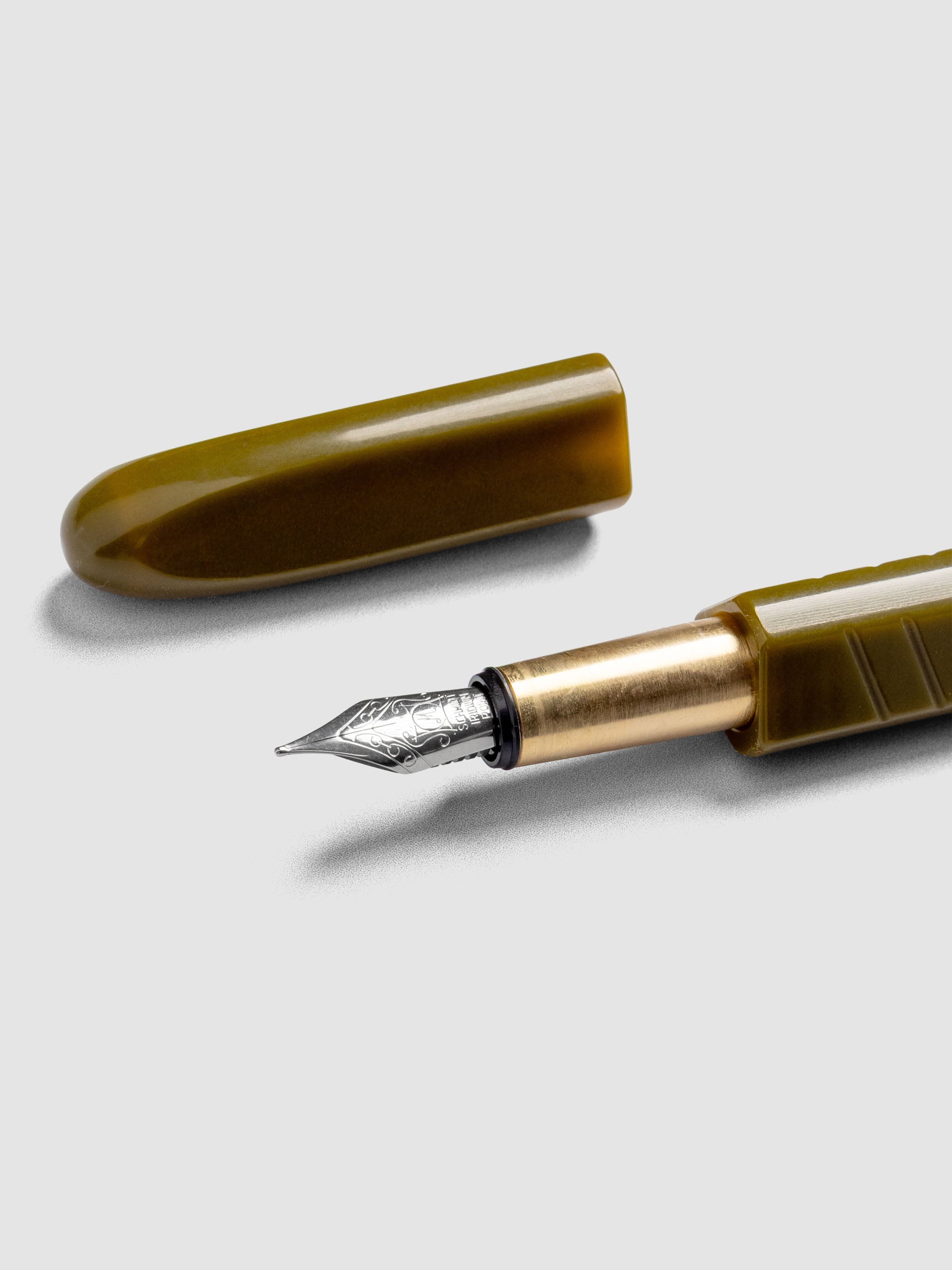 Kolo Tino Fountain Pen in the color Acrylic Wasabi, a warm green barrel with brass accents and a silver medium nib shown with cap off.