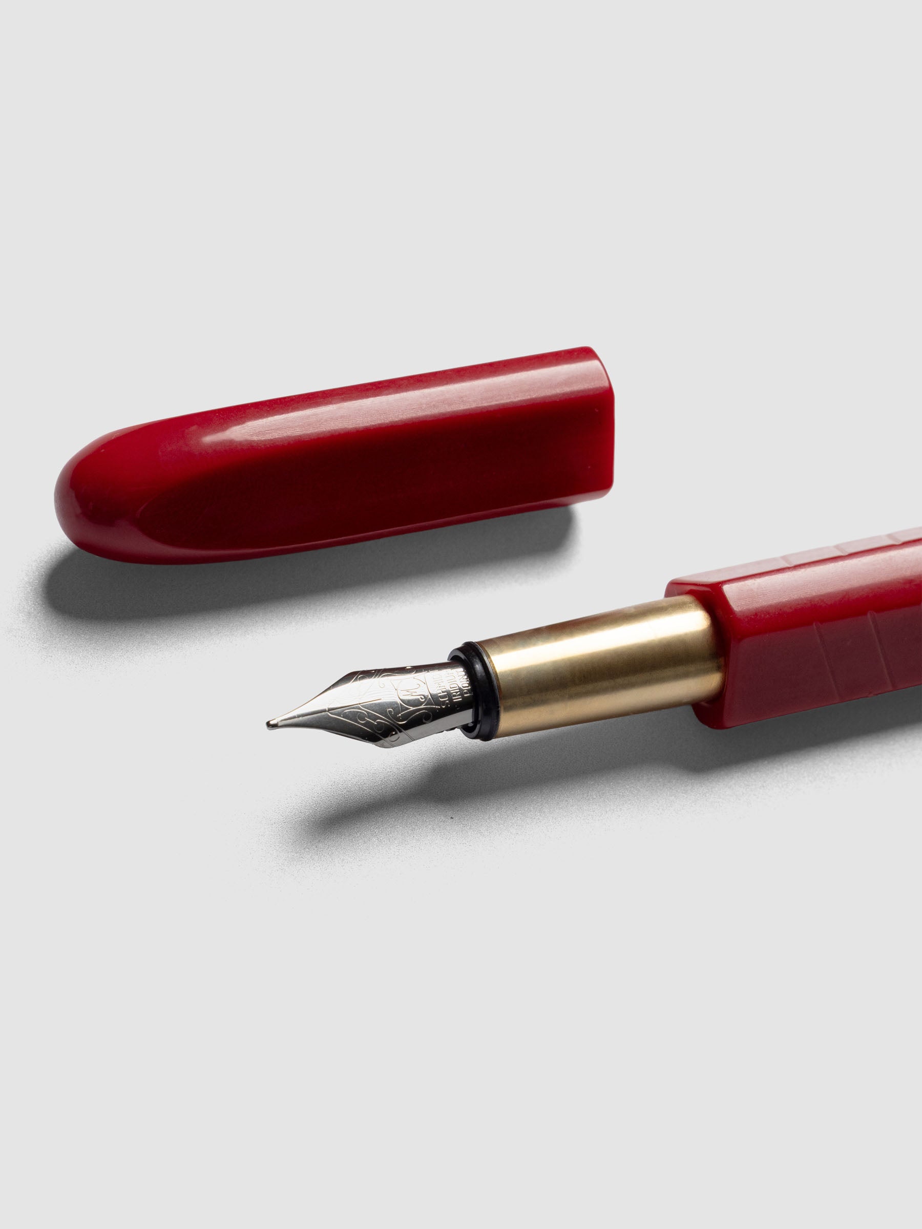 Kolo Tino Fountain Pen in the color Acrylic San Marzano, a tomato red barrel with brass accents and a silver medium nib shown with cap off.