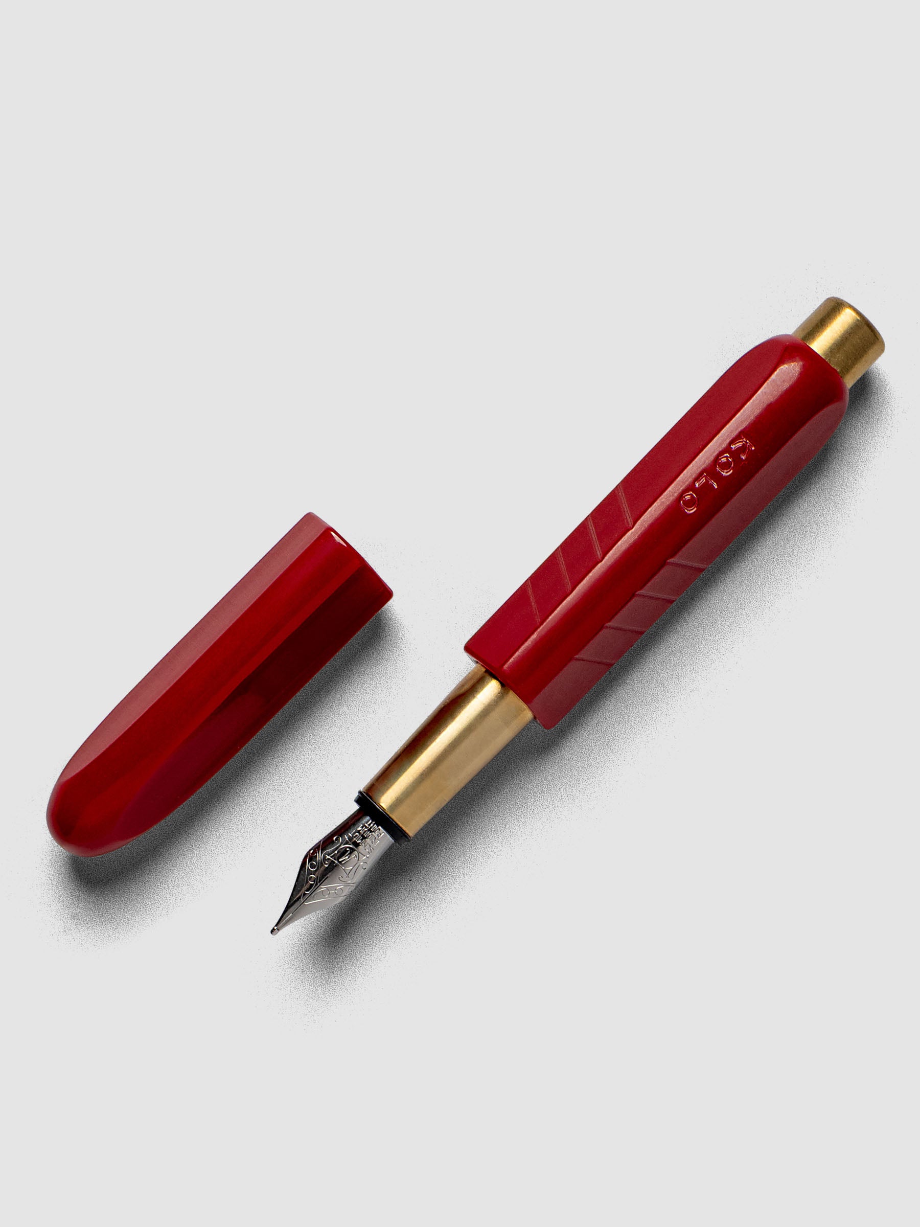 Kolo Tino Fountain Pen in the color Acrylic San Marzano, a tomato red barrel with brass accents and a silver medium nib shown with cap off.