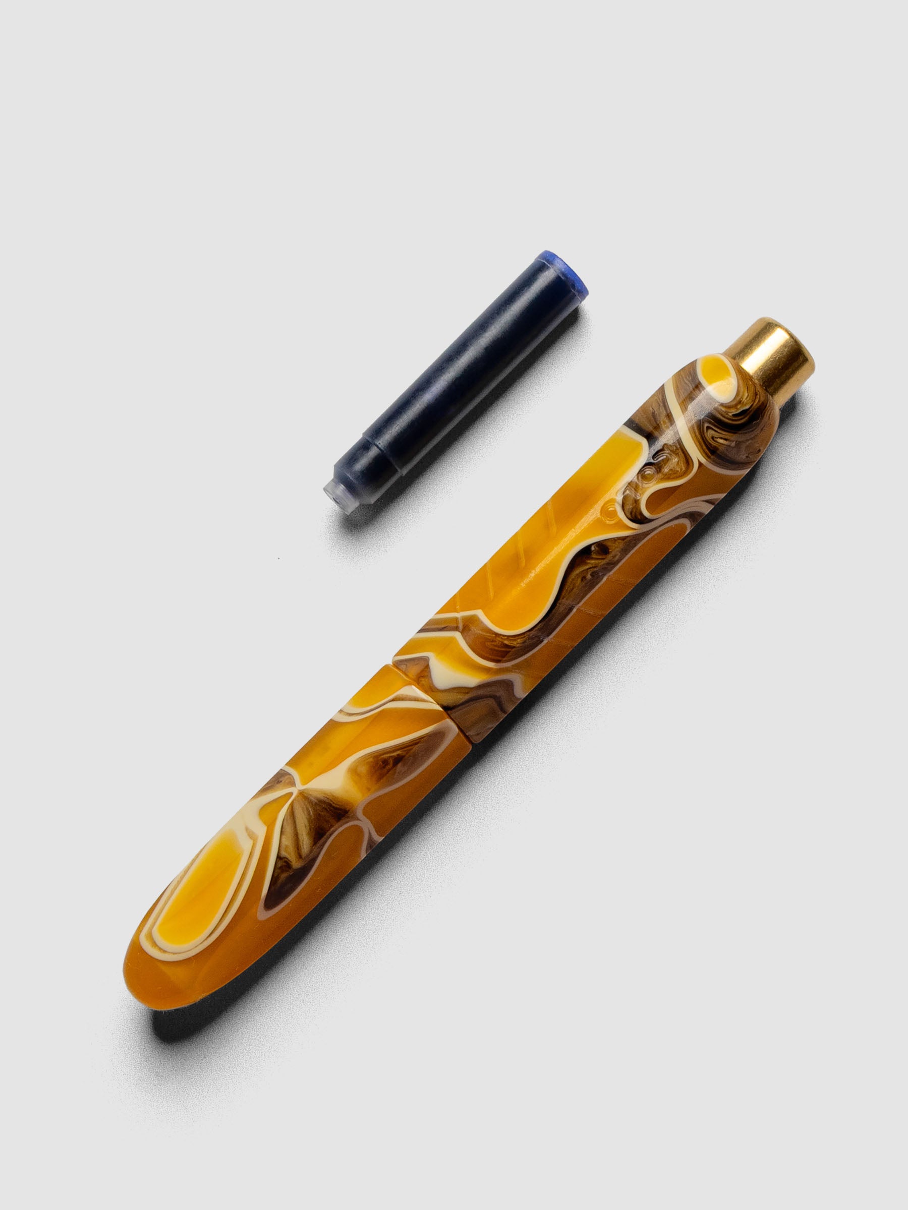 Kolo Tino Fountain Pen in the color Dune, a variegated yellow, brown, and beige barrel. Shown with cap on and ink cartridge resting beside pen.