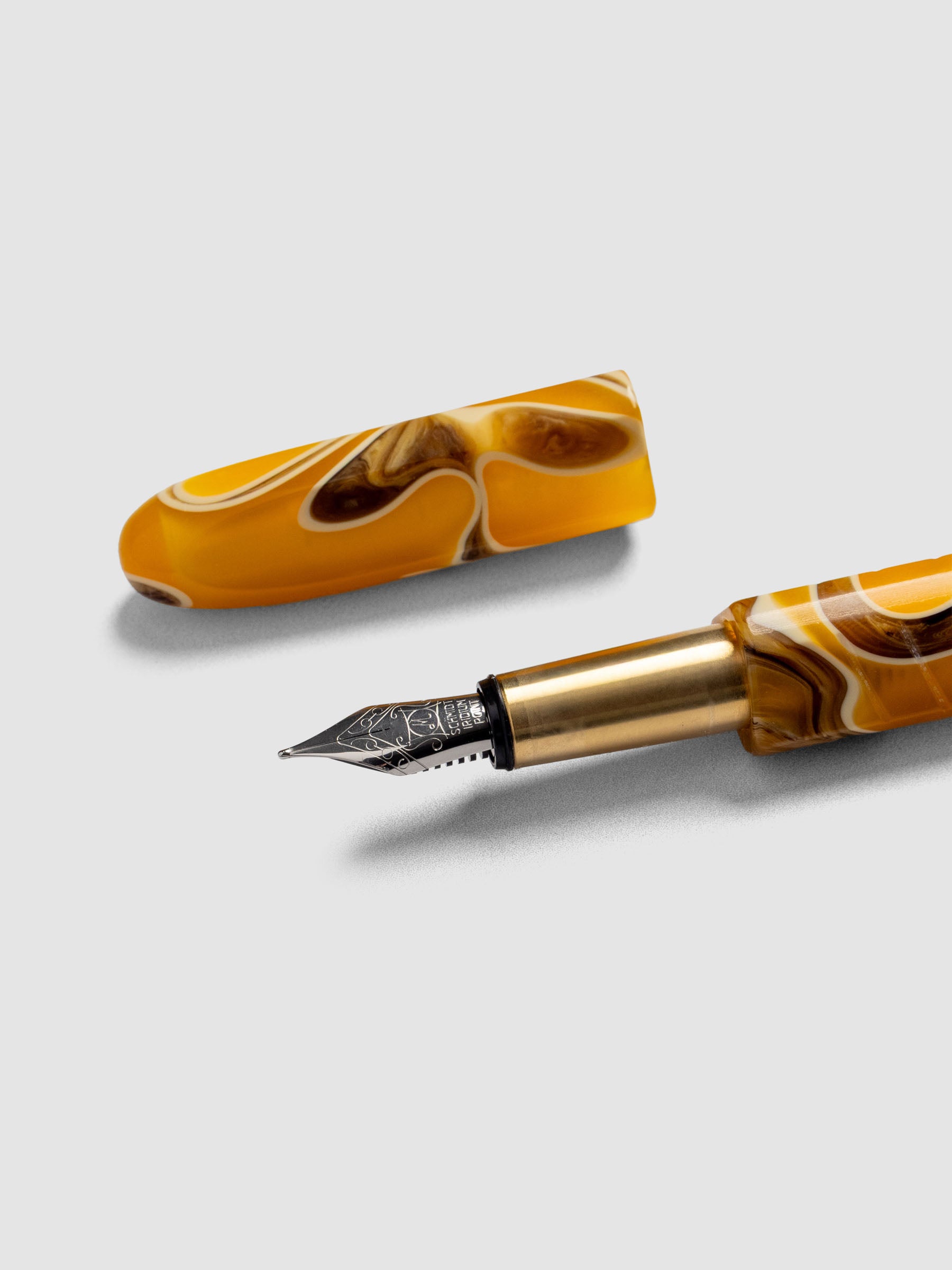 Kolo Tino Fountain Pen in the color Dune, a variegated yellow, brown, and beige barrel with brass accents and a silver medium nib shown with cap off.
