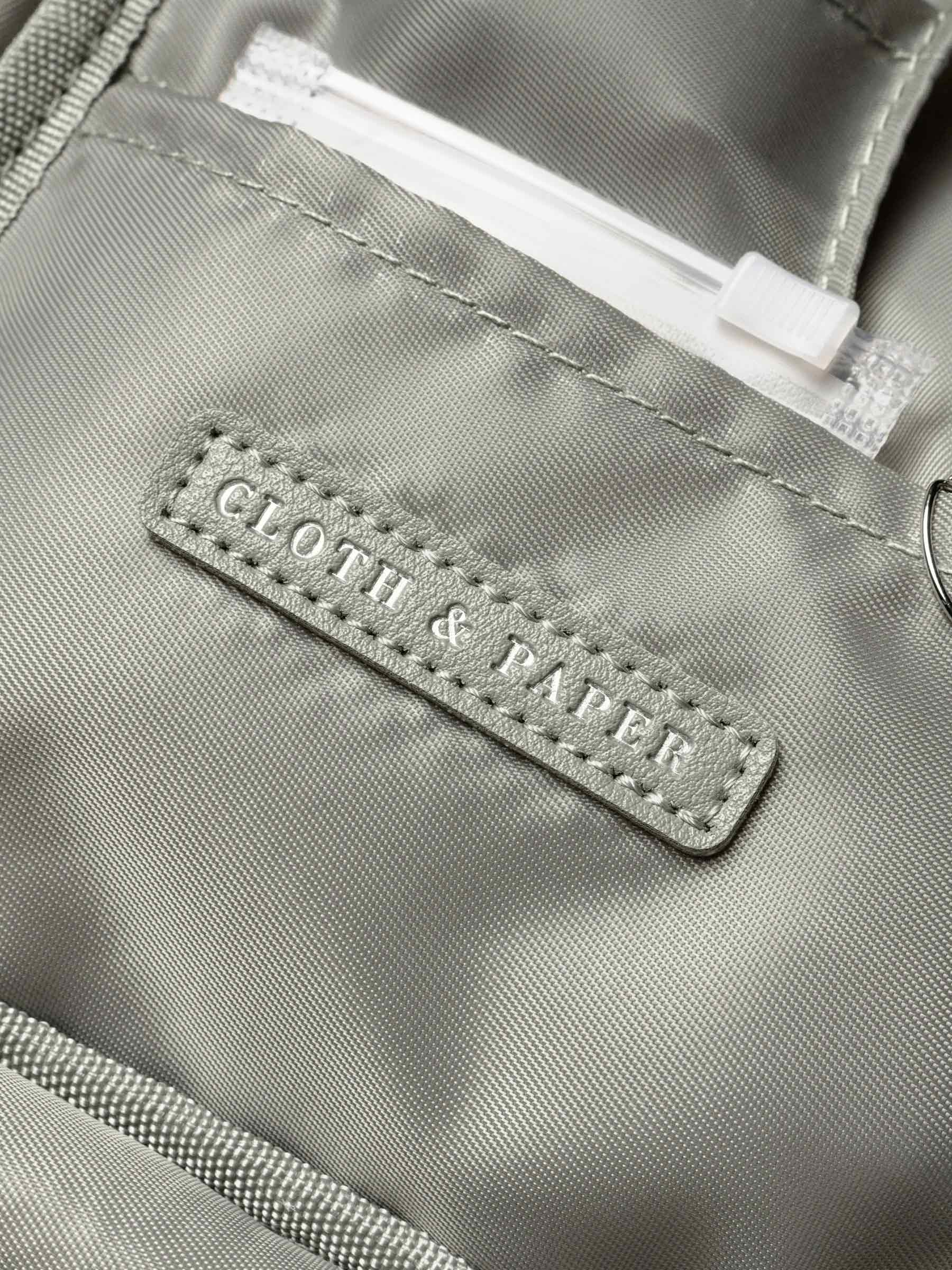 Close-up of the Cloth & Paper stitched logo tag inside the Ristretto Fountain Pen Travel Case, showing smooth sage green nylon fabric.