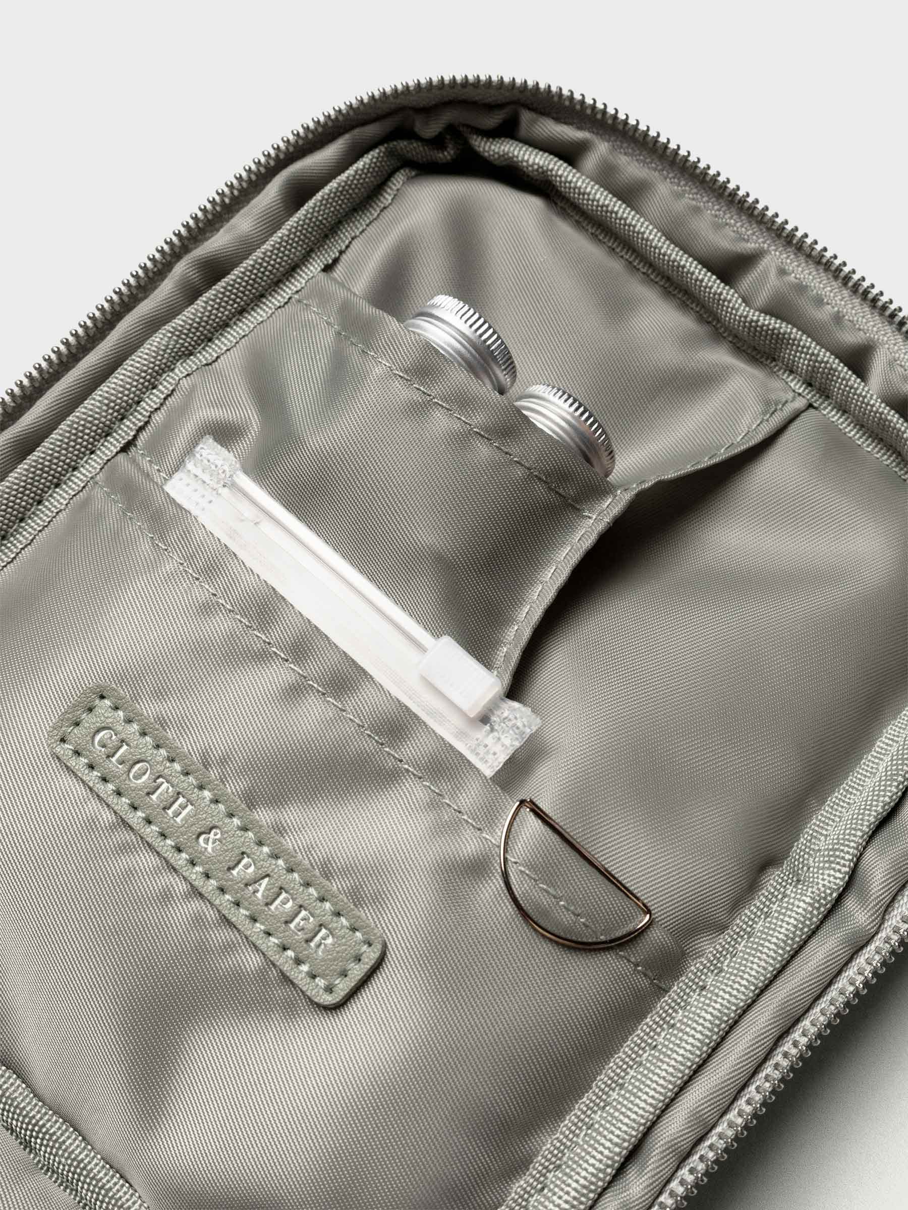 Interior view of the case with small pockets holding silver ink vials and accessories, along with a silver paper clip.